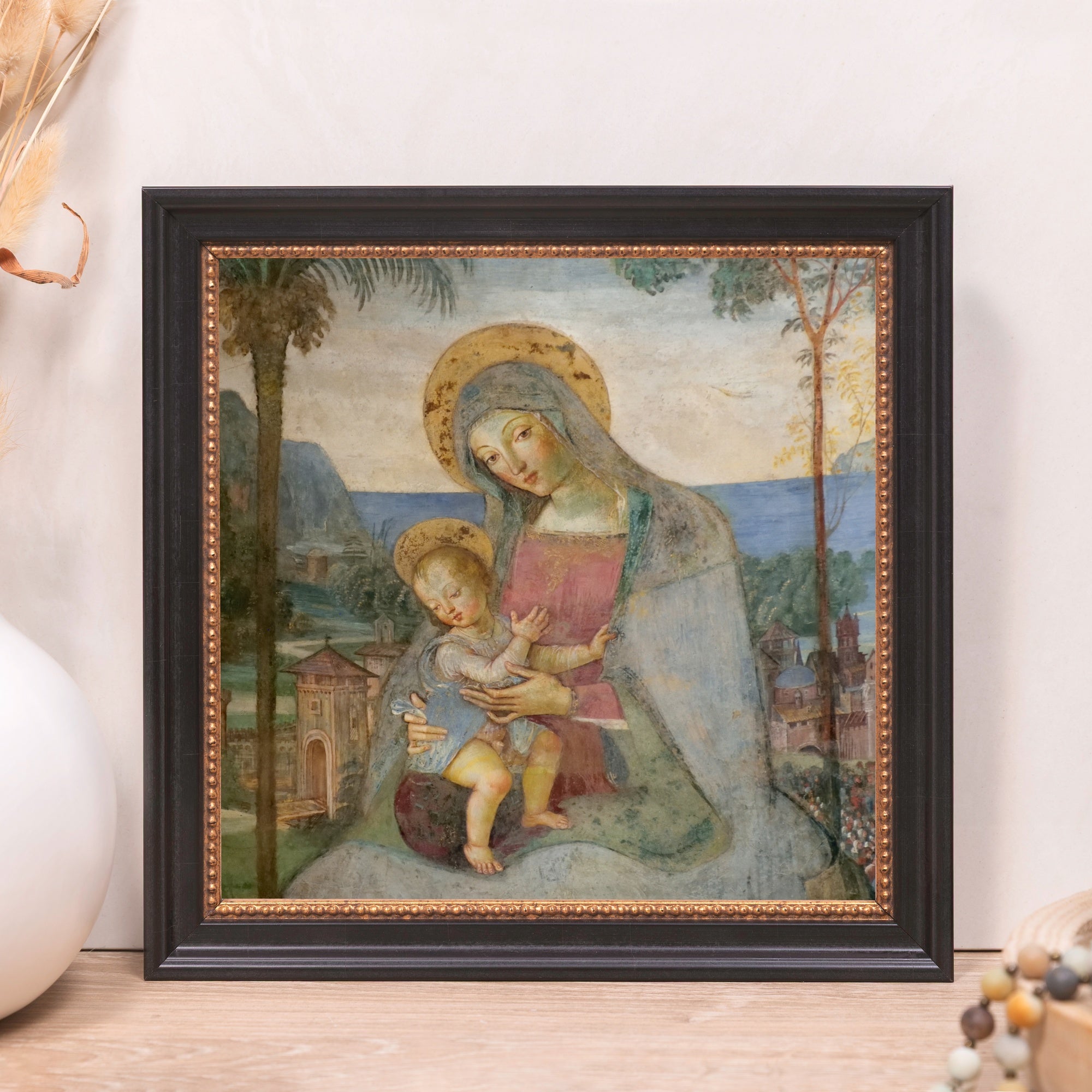 Framed Madonna and child art print with gold detail and black frame.