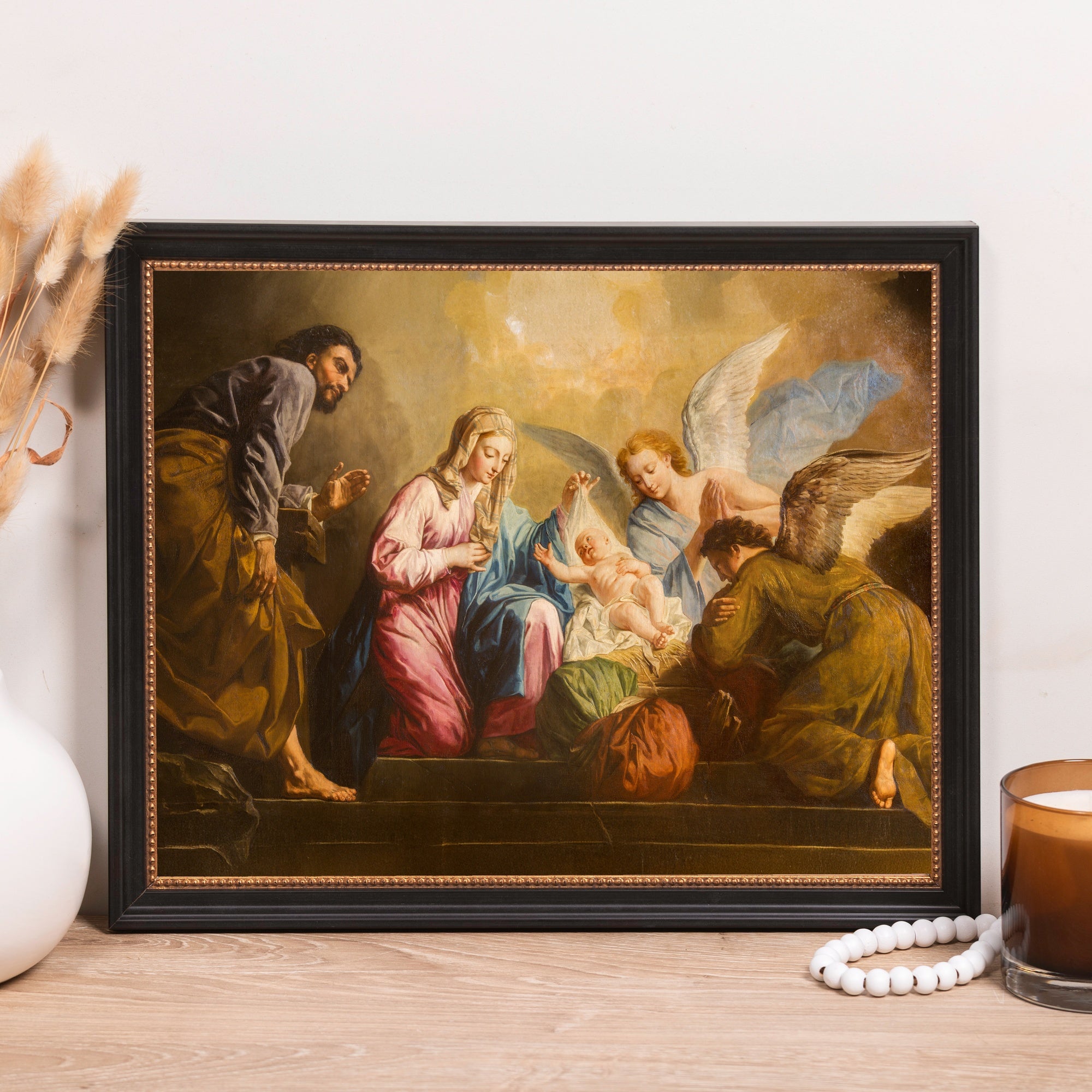 Framed Painting depicting the Nativity with Mary, Joseph, angels, and baby Jesus in earth tones and black frame.
