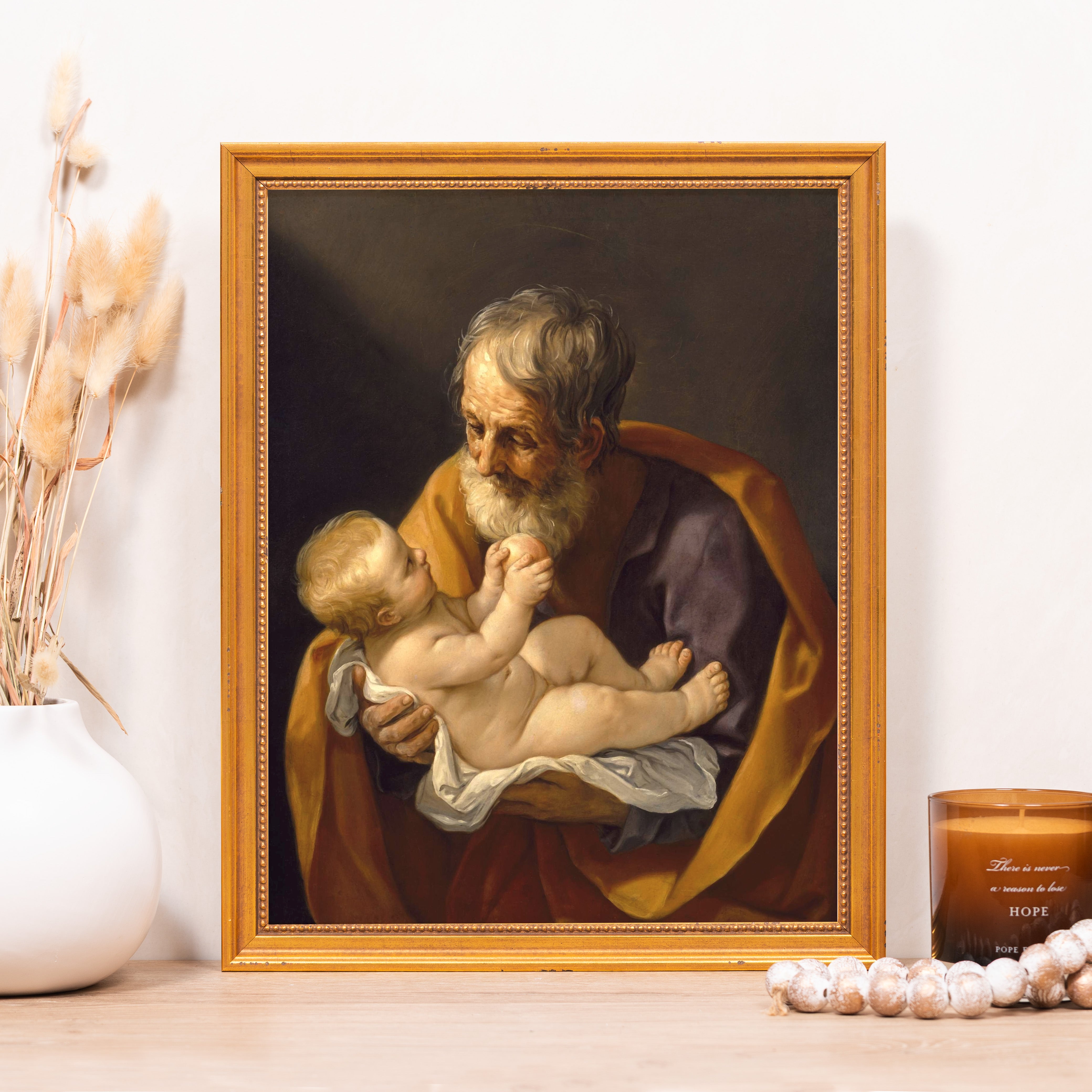 Framed print of Saint Joseph Holding Baby Jesus in golden frame.