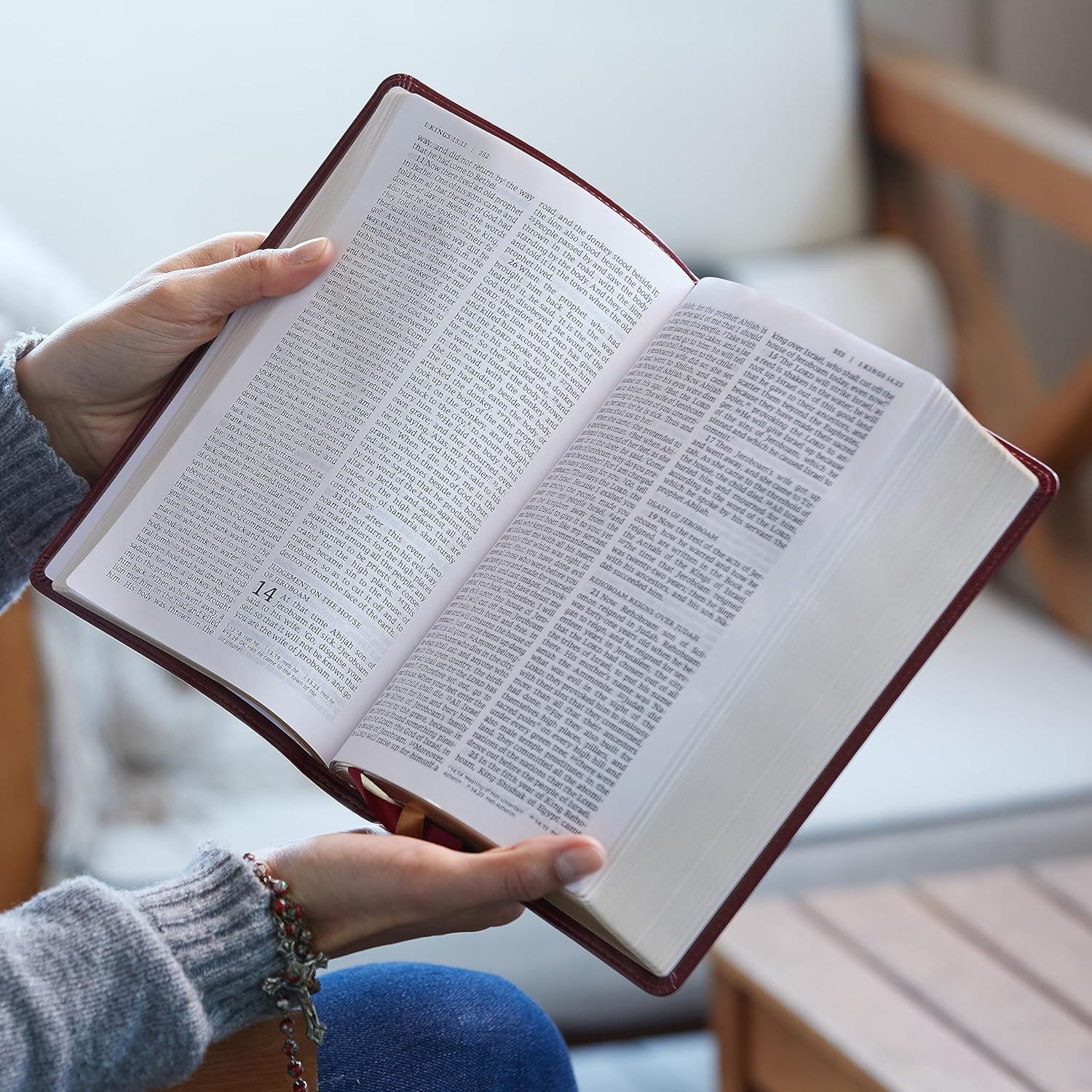 Holding Open Bible With Burgundy Cover And Cream Pages.