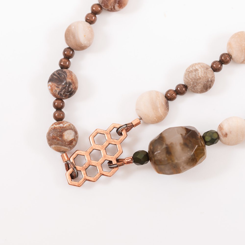 Beaded necklace with brown stones, copper hardware, and a honeycomb-shaped clasp detail.