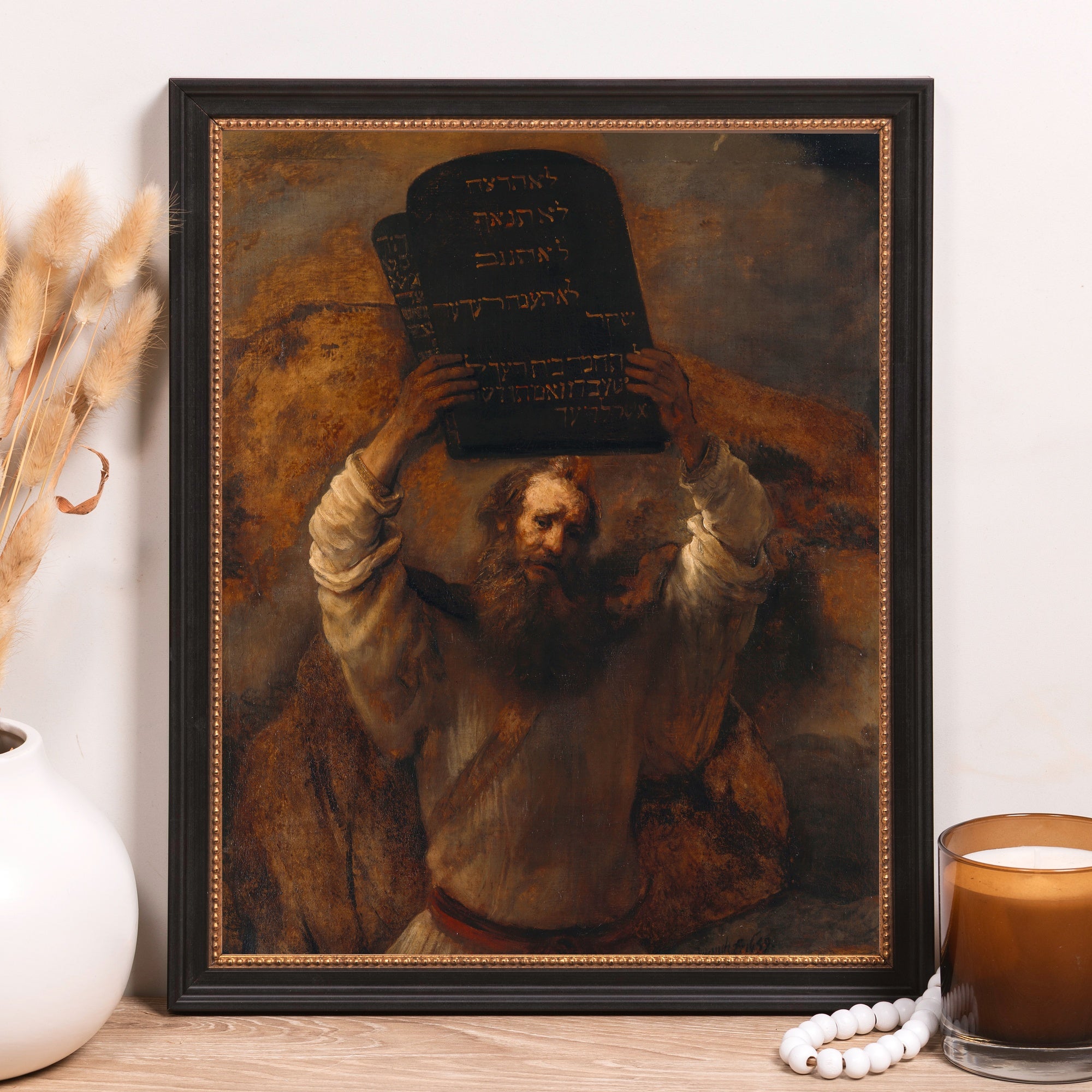 Framed "Moses" painting with Ten Commandments tablets in Hebrew, in a dark color palette, black frame with gold trim, for wall decor.