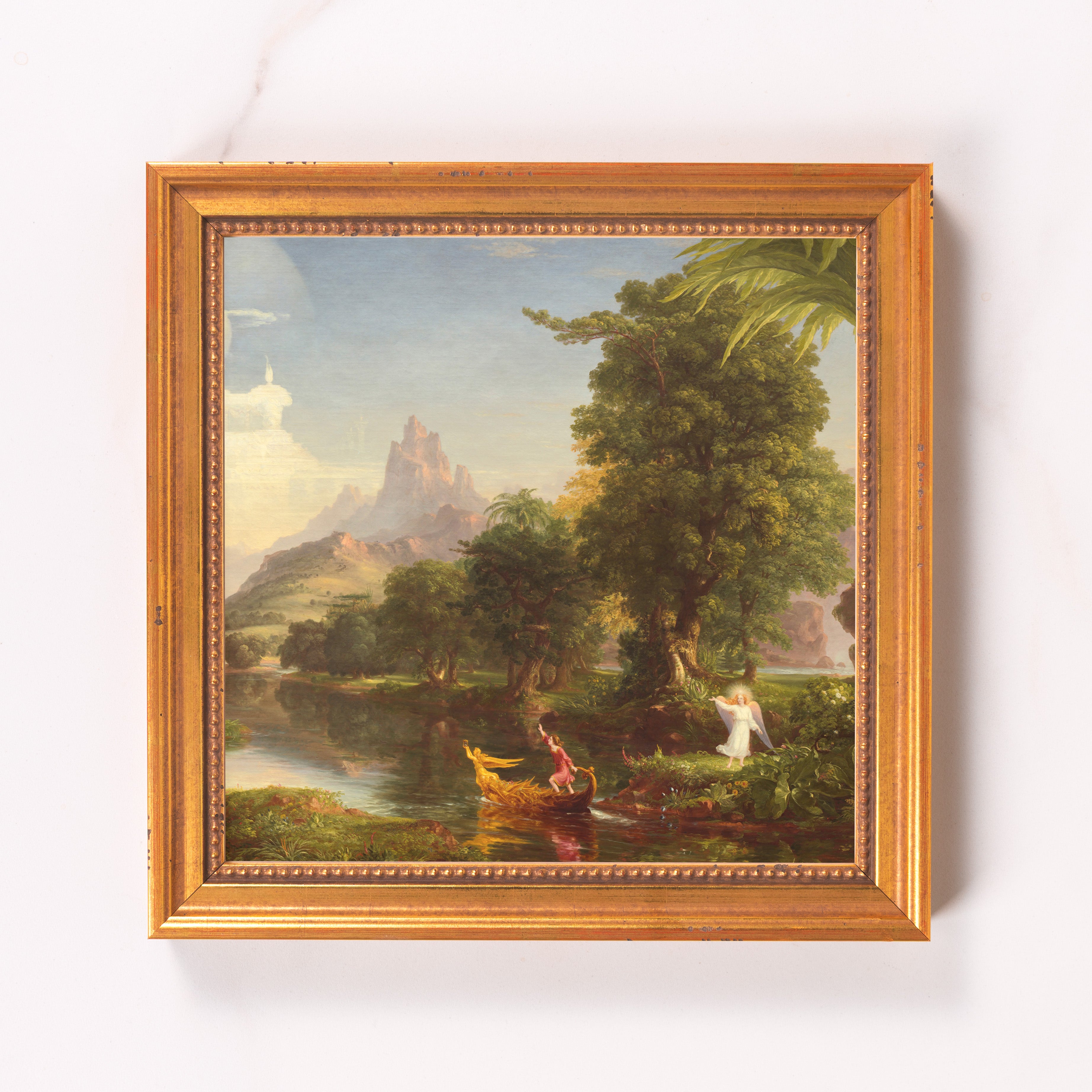 Framed painting of lush landscape with river, figure in boat, and angel.