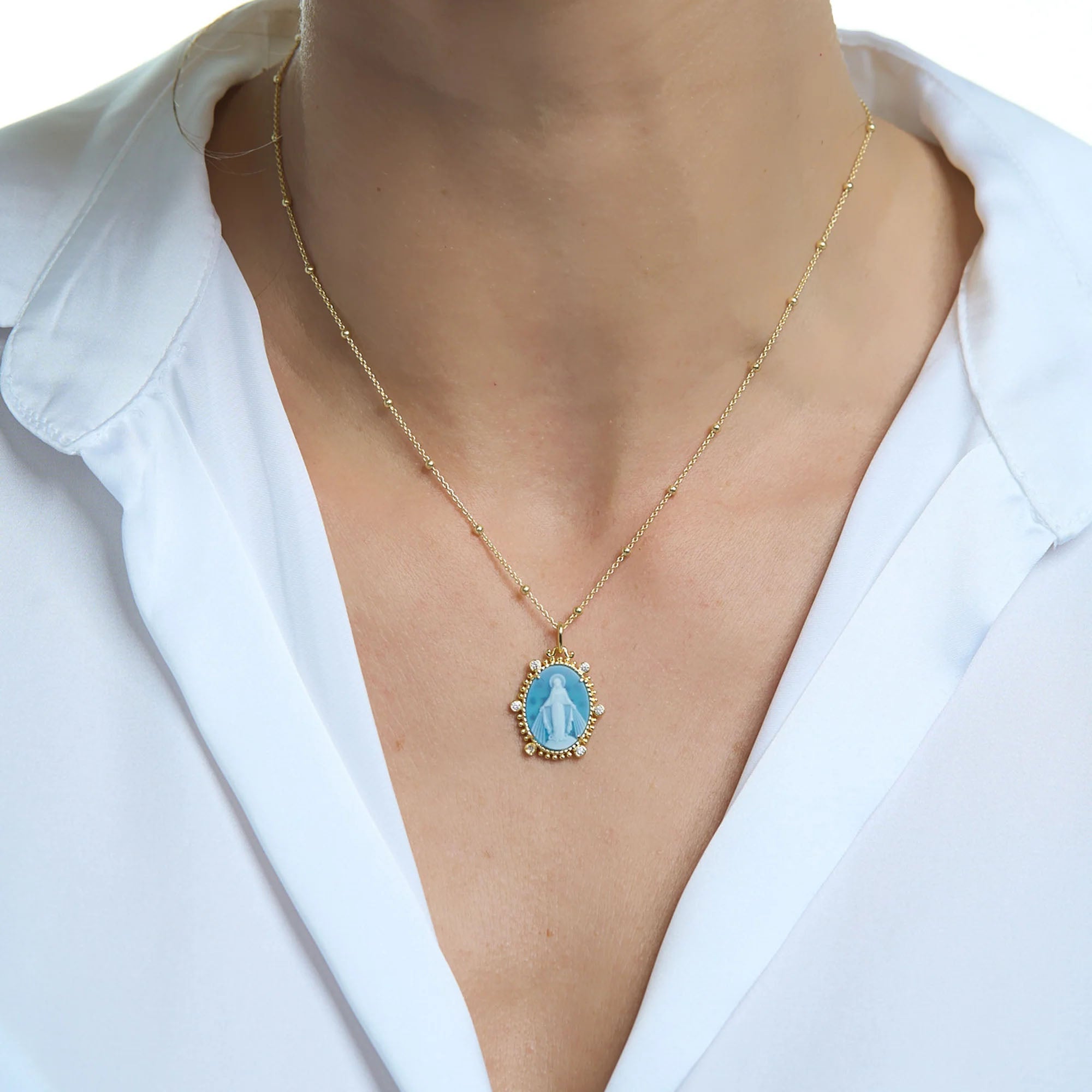 Necklace features a golden chain and an oval blue enamel Virgin Mary pendant.
