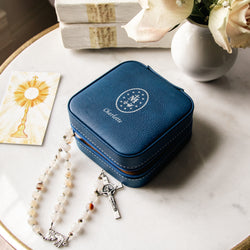 Personalized, blue, faux-leather rosary travel case with white embroidery and zipper closure.