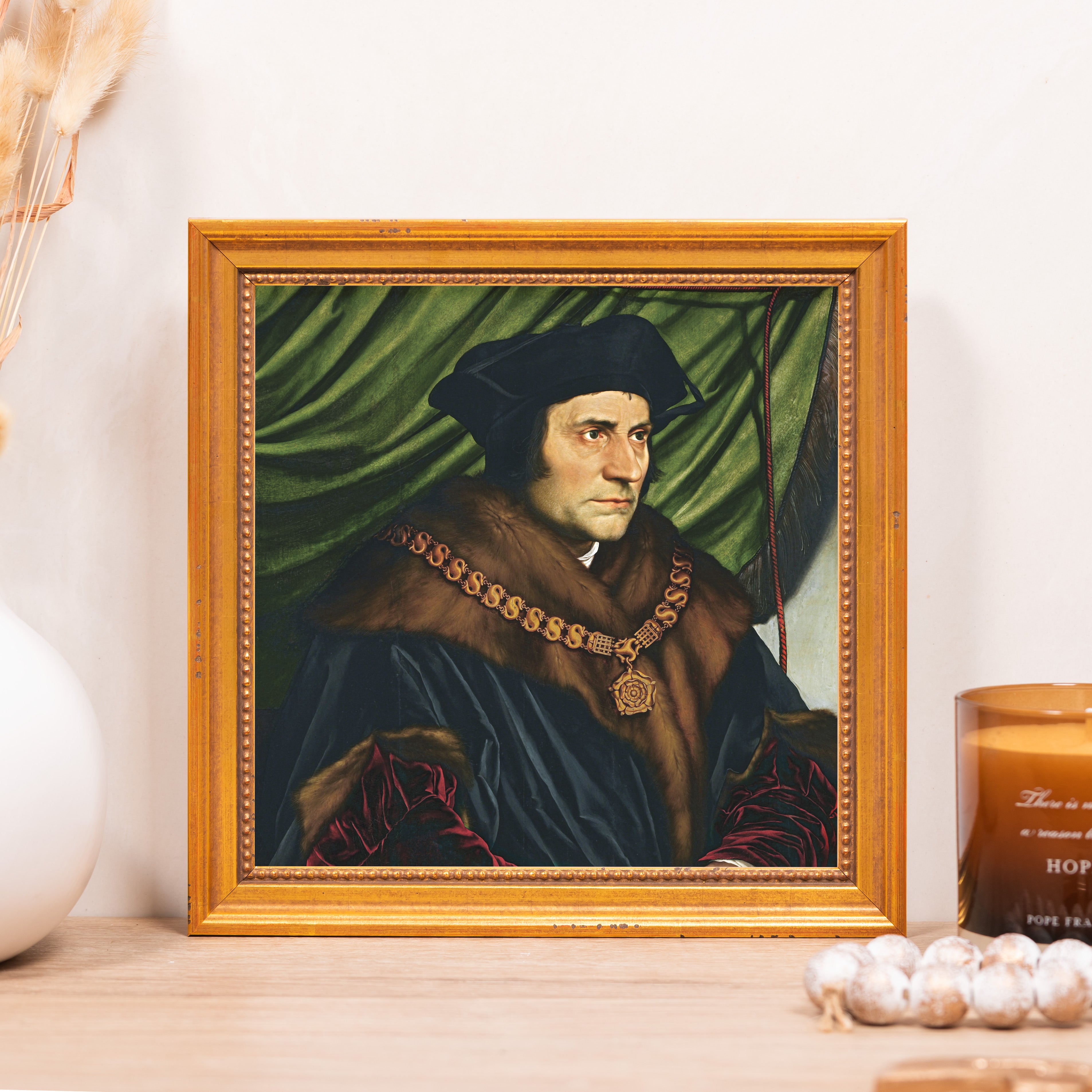 Framed portrait print of a man with fur collar and gold chain, in gold frame.