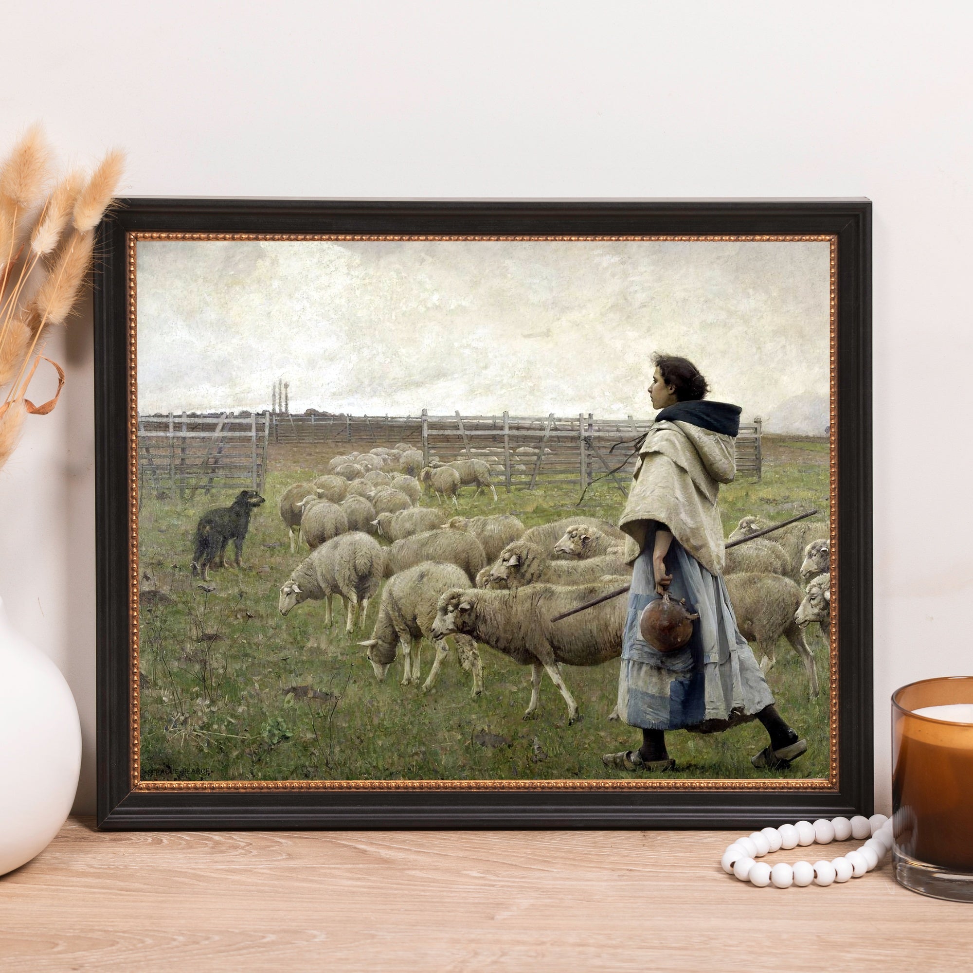 Framed art print depicting a woman herding sheep, black and gold frame.