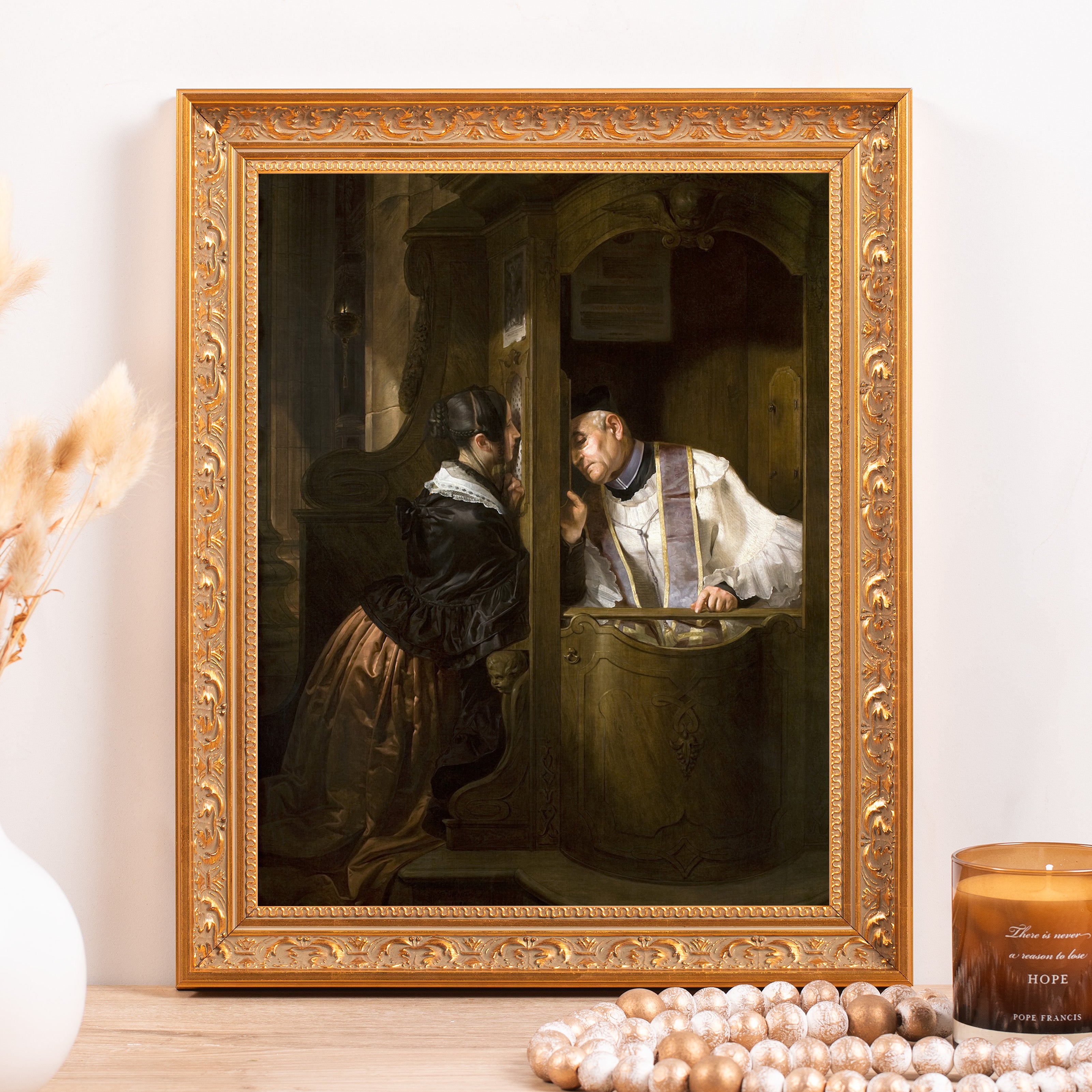 Framed print of a woman confessing to a priest in an ornate gold frame, styled with beads and a candle that says "Hope.".