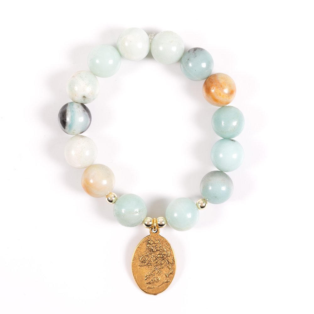 Beaded bracelet with various light-colored stone beads and an oval, golden charm.