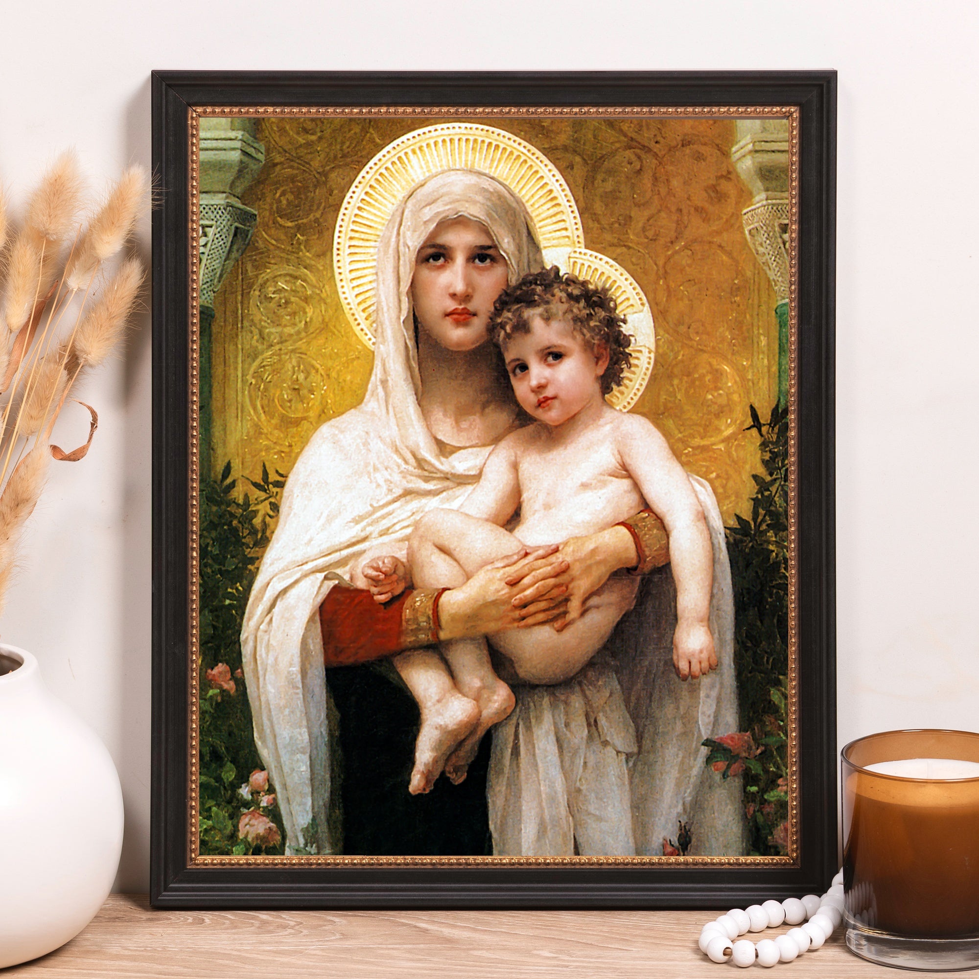 Framed artwork shows painting of Mary holding baby Jesus, vintage style, gold accents, dark frame.