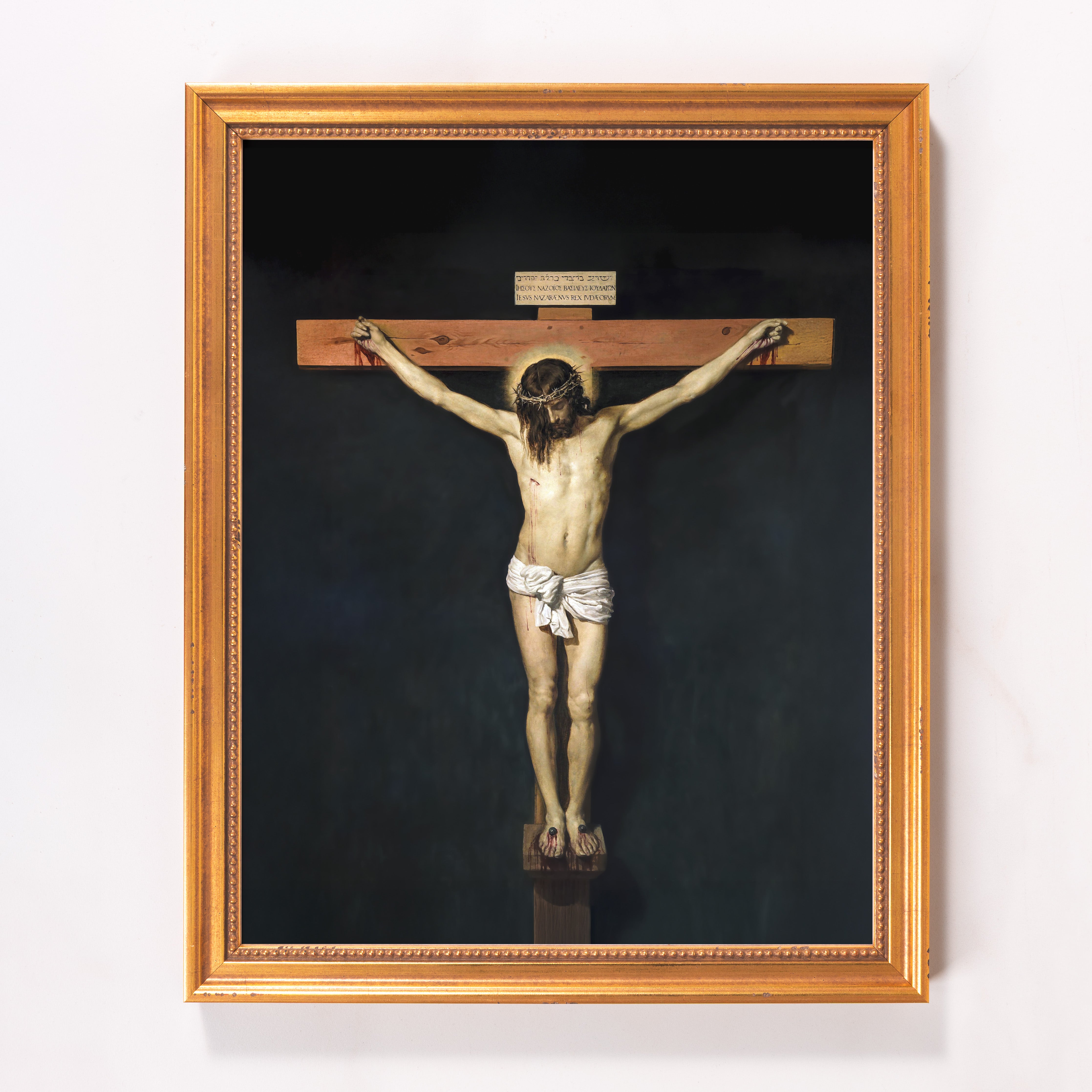 Framed painting depicts Jesus on the cross with gold frame and dark background, capturing a classical, religious style.