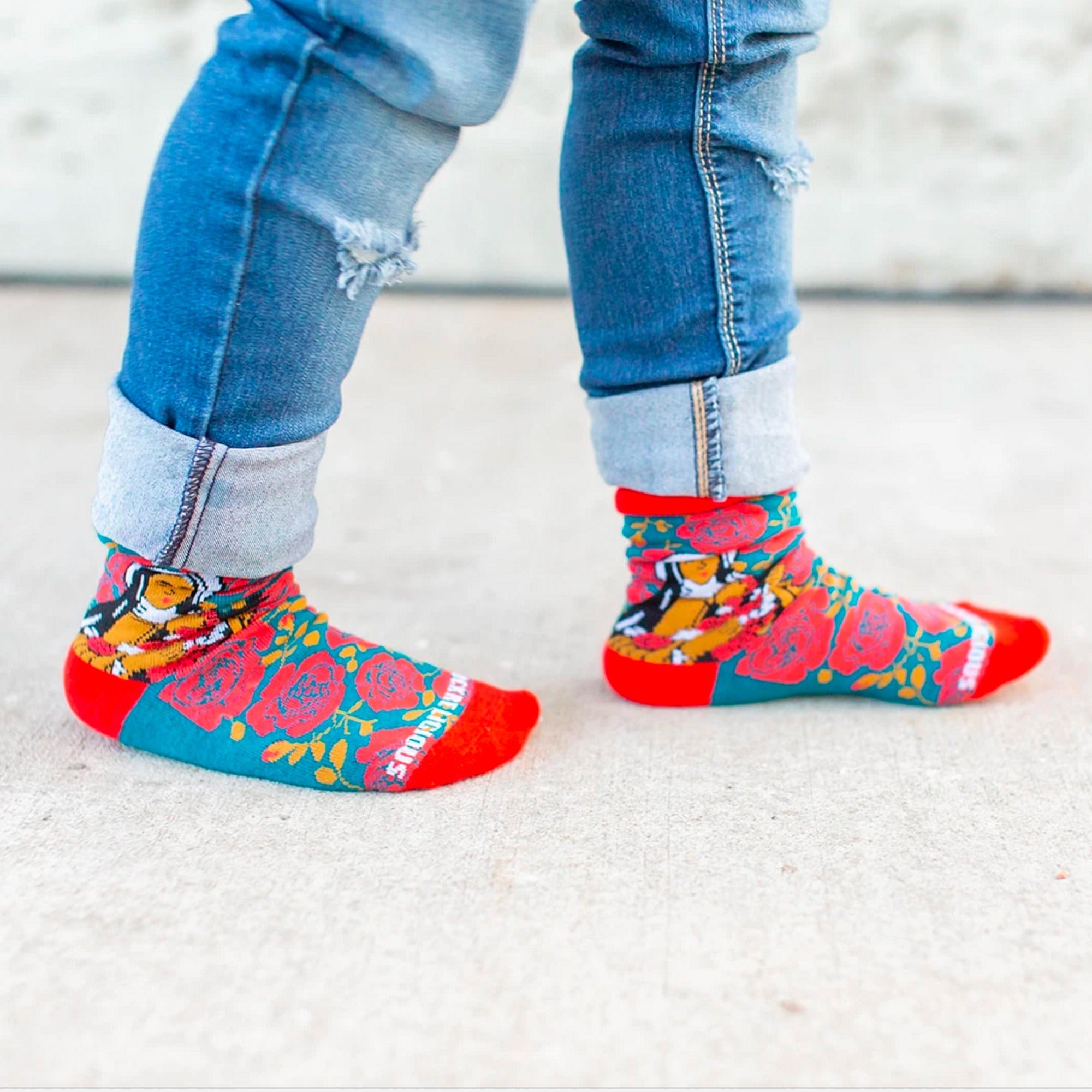 Novelty Socks feature a turquoise floral pattern and red toe/cuff, worn with cuffed jeans.
