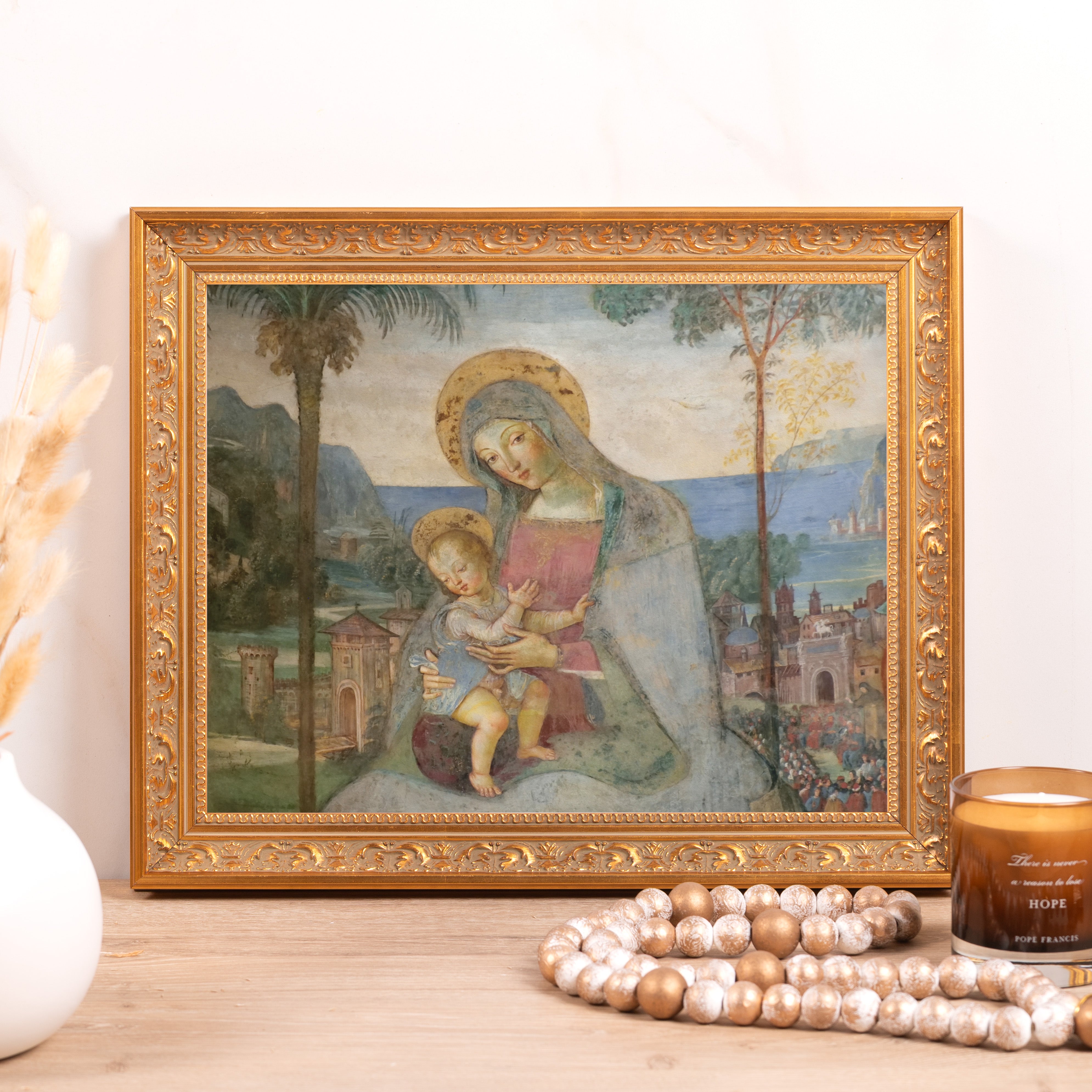Framed print depicting the Madonna and Child with a landscape background and ornate gold frame.