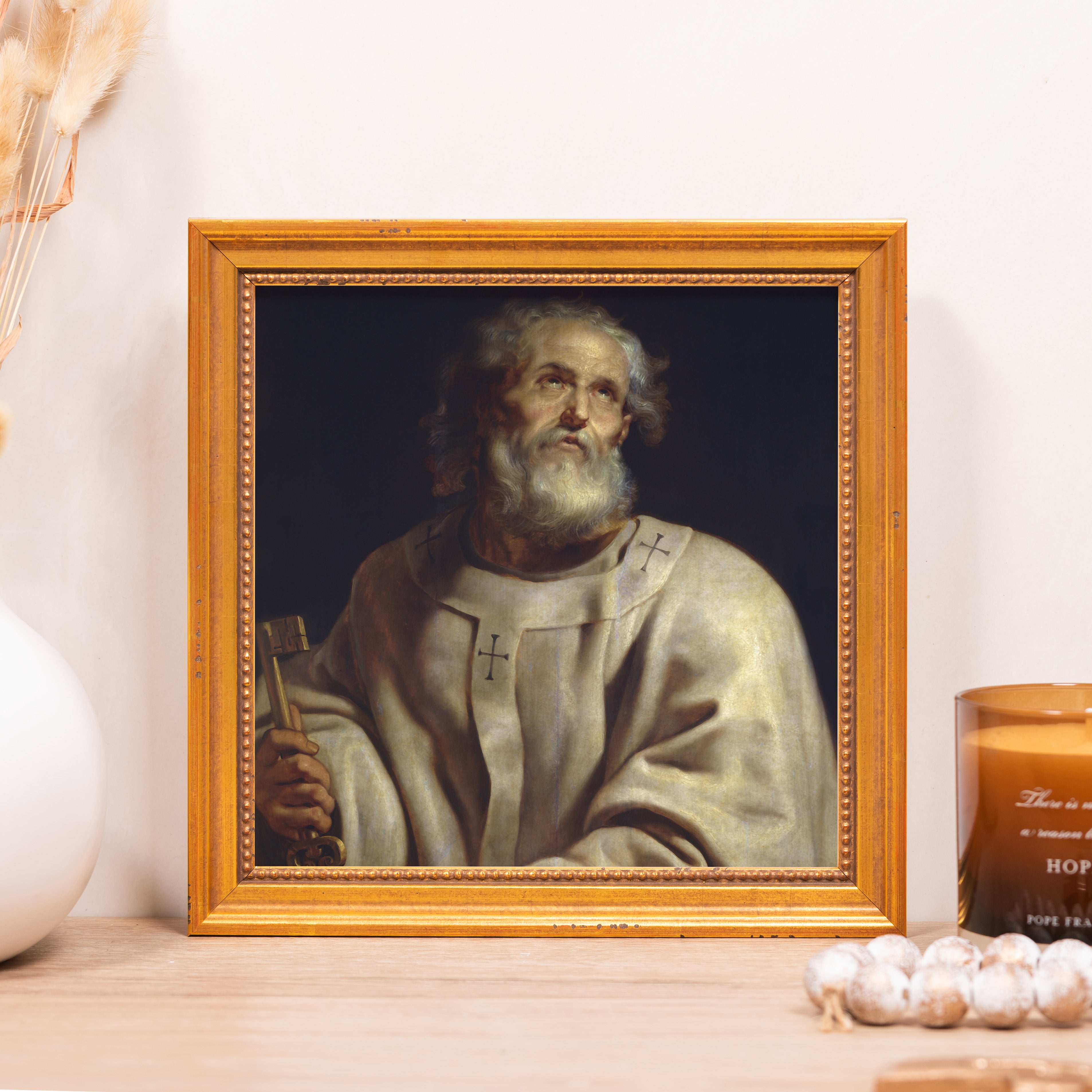 Framed painting of Saint Peter holding a key, gold frame, neutral background.