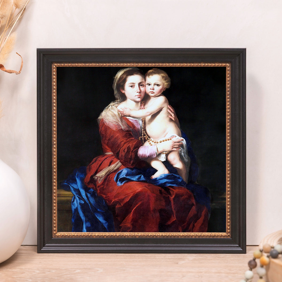 Framed print featuring oil painting of mother and child, with red and blue garments, black frame.