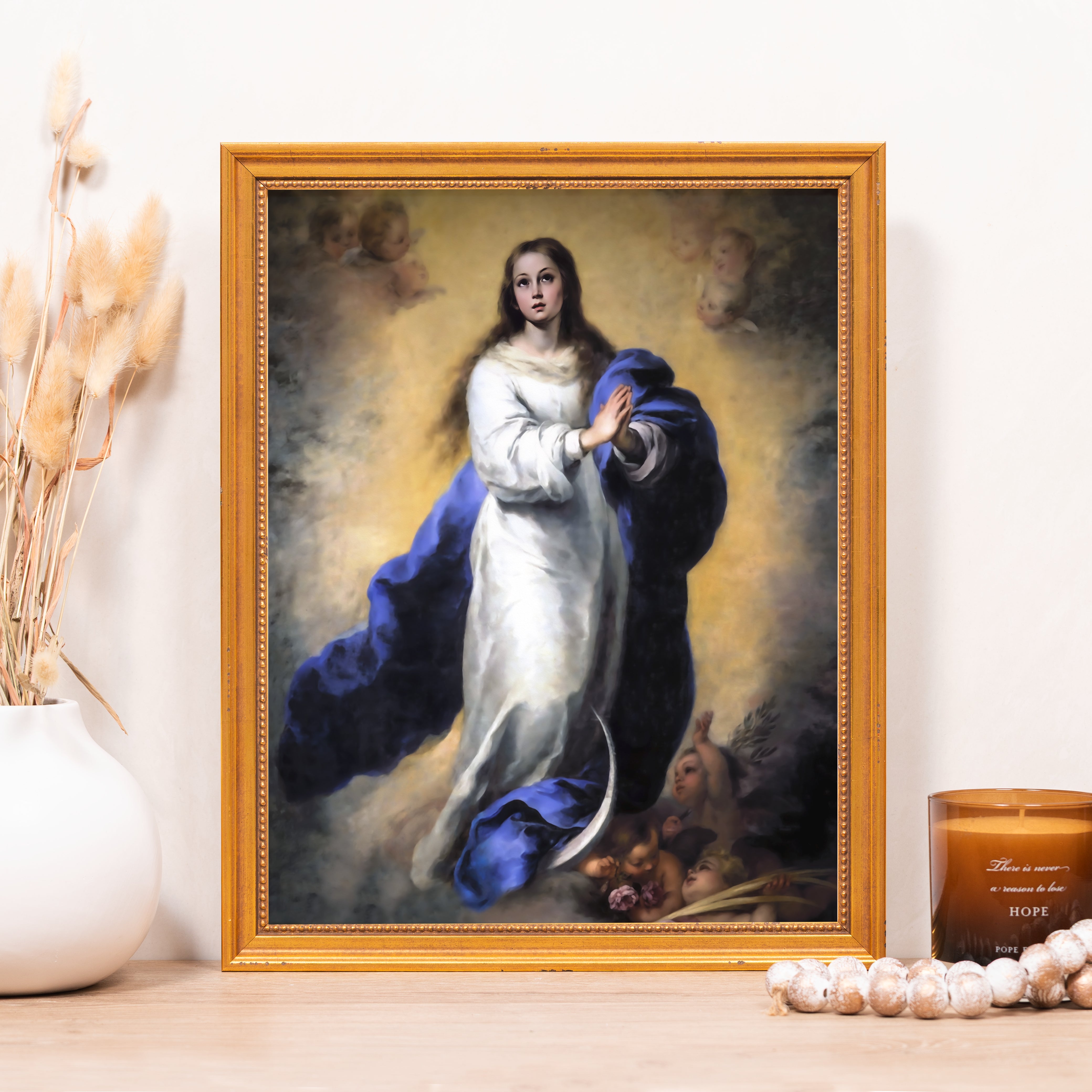 Framed painting of woman with angels, in white robe and blue cloak, with a gold frame.