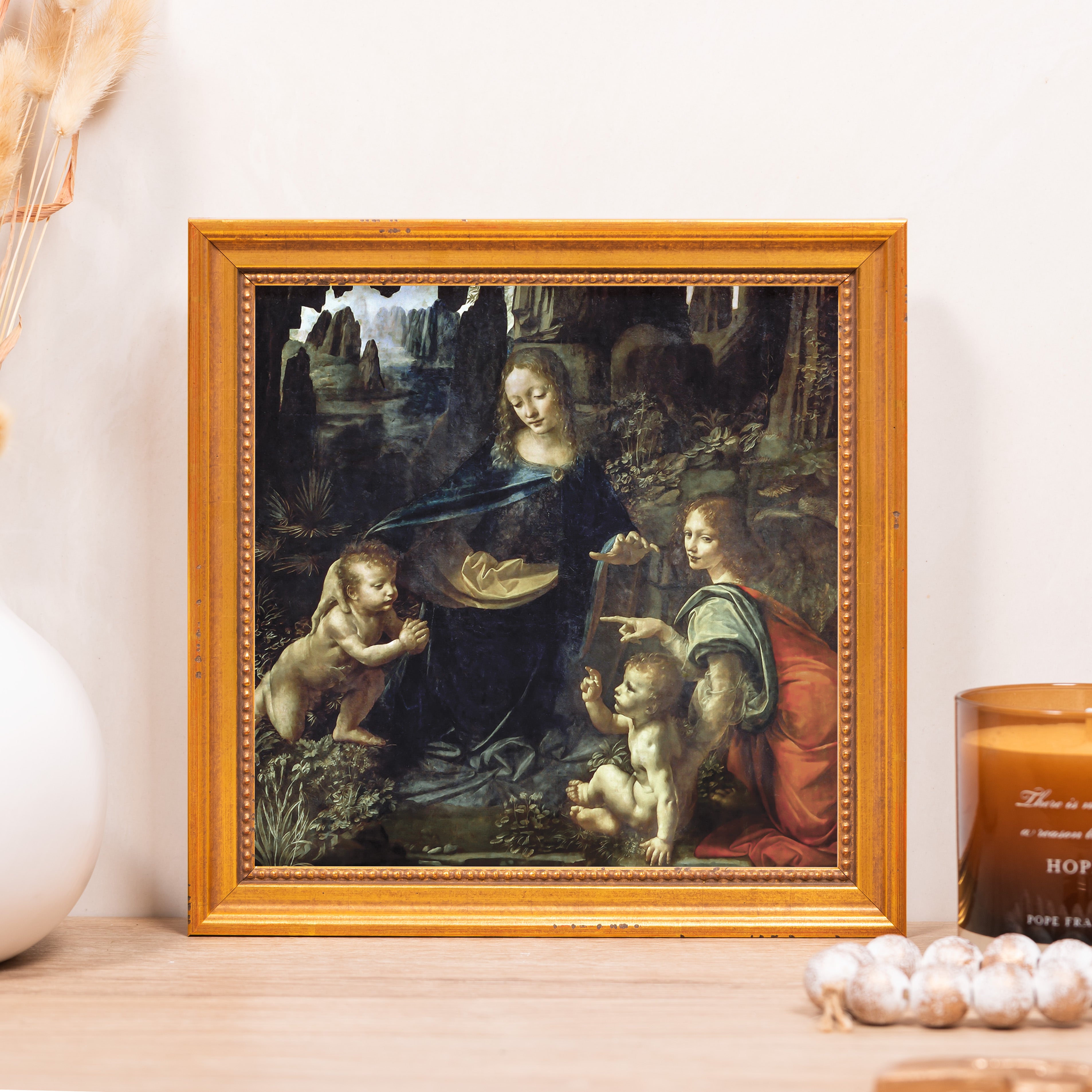 Framed reproduction of Madonna of the Rocks painting in a decorative gold frame.