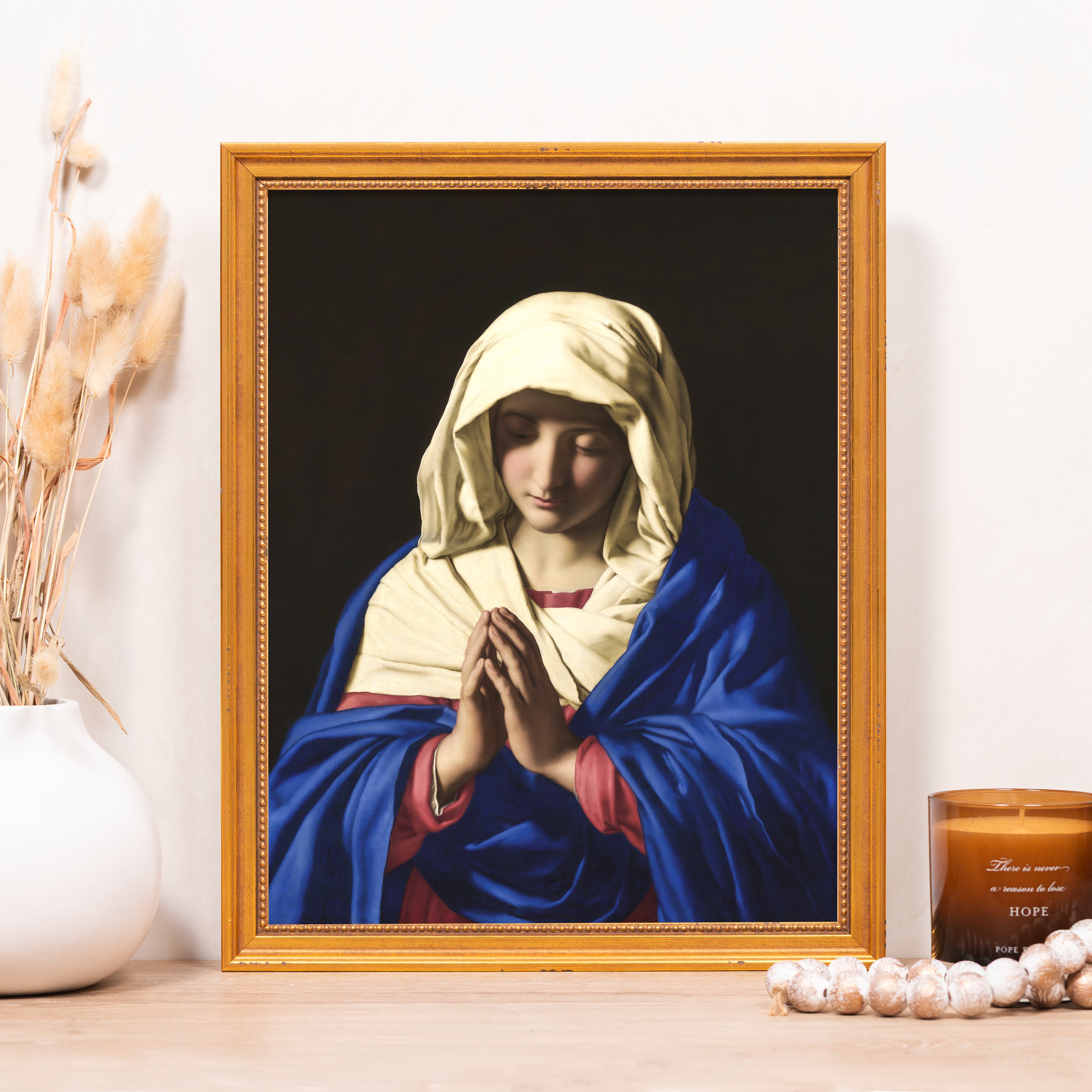 Framed artwork of praying Mary in blue cloak, with gold frame, for religious decor.