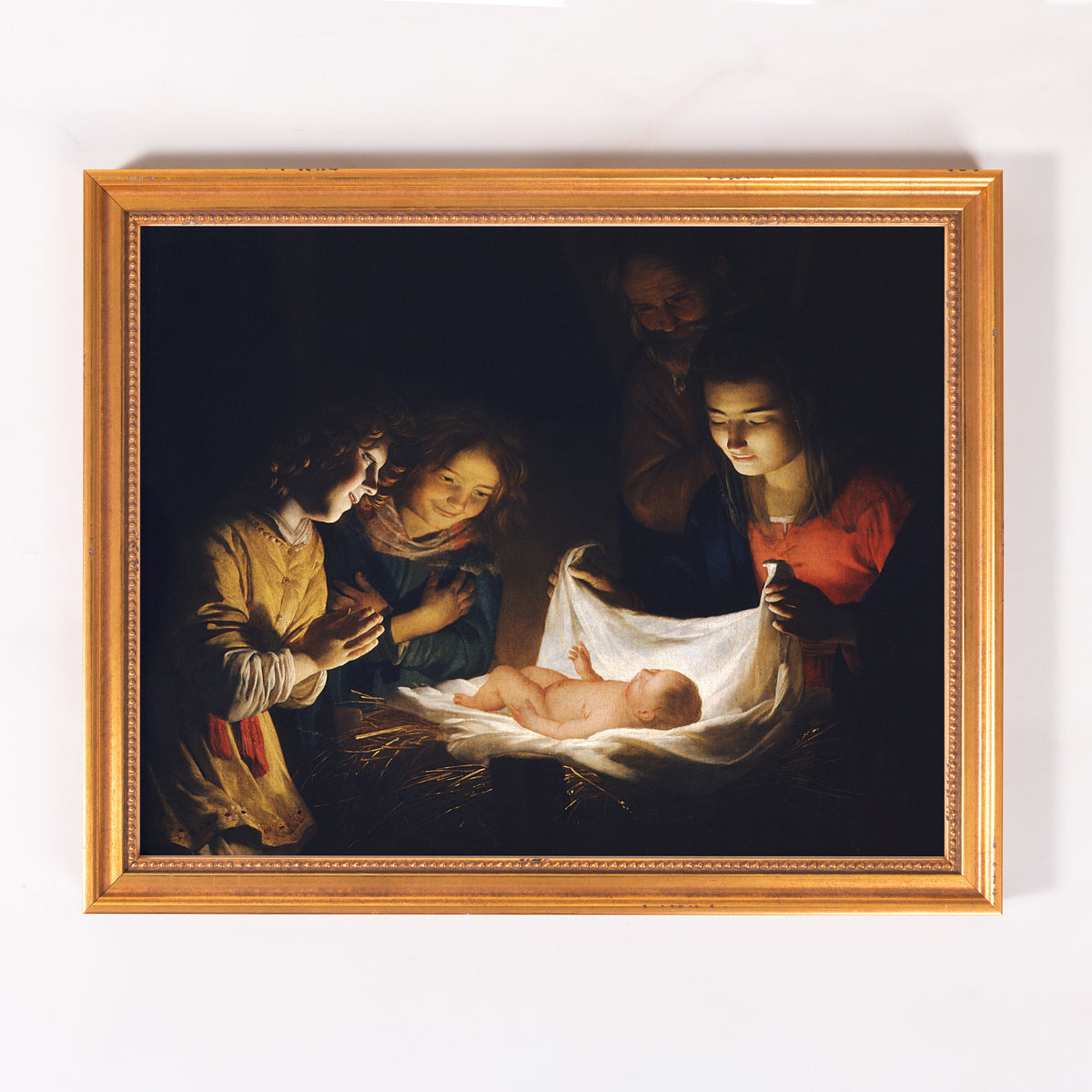 Framed Nativity artwork: Painted figures celebrate baby Jesus in a manger, gold frame.