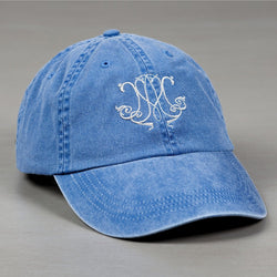Blue, cotton baseball cap with an embroidered, swirling, white monogram.