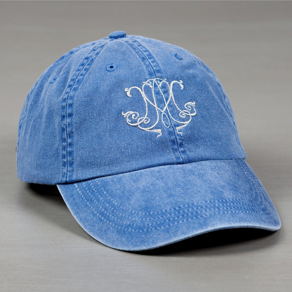 Blue, cotton baseball cap with an embroidered, swirling, white monogram.
