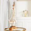 Our Lady Of Fatima religious statue with jeweled white cloak and golden crown on a wooden base.