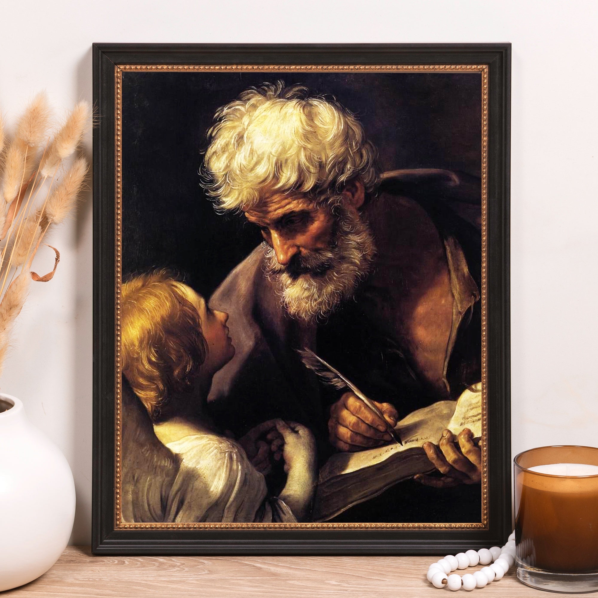 Framed art print of "St. Matthew and the Angel," black and gold frame, classical style.