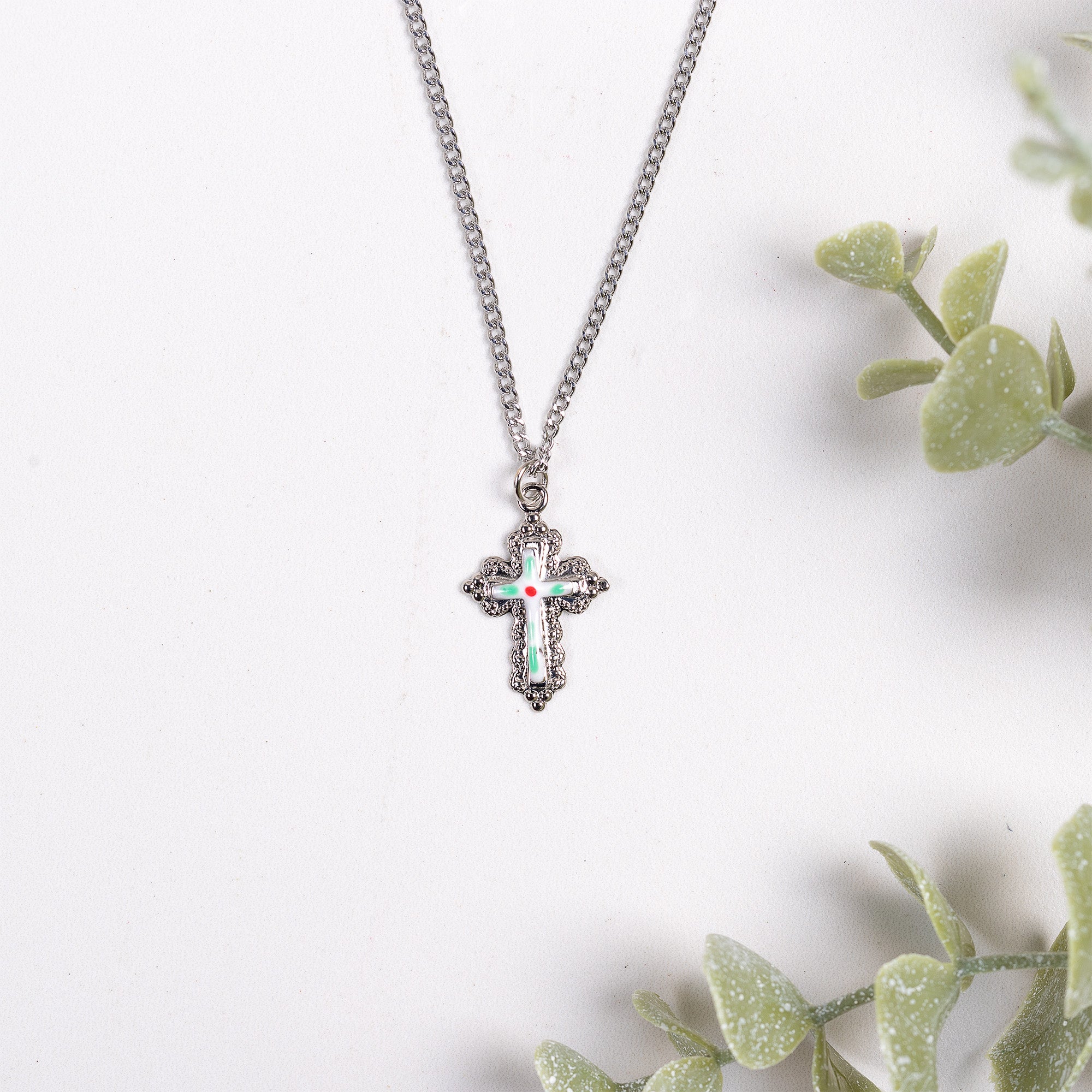 Silver chain necklace with green, white, and red enamel cross pendant.