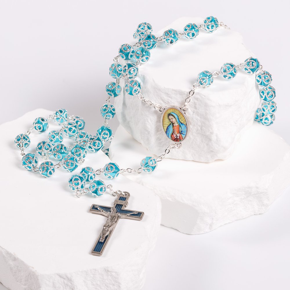Turquoise Rosary with metal accents and a crucifix displayed on a white surface.