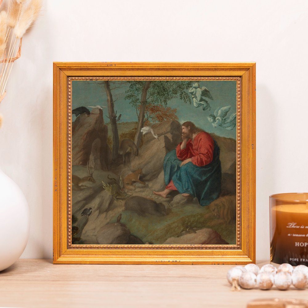 Framed print depicting Jesus, in red and blue robes, sitting in the wilderness, with a gold frame.