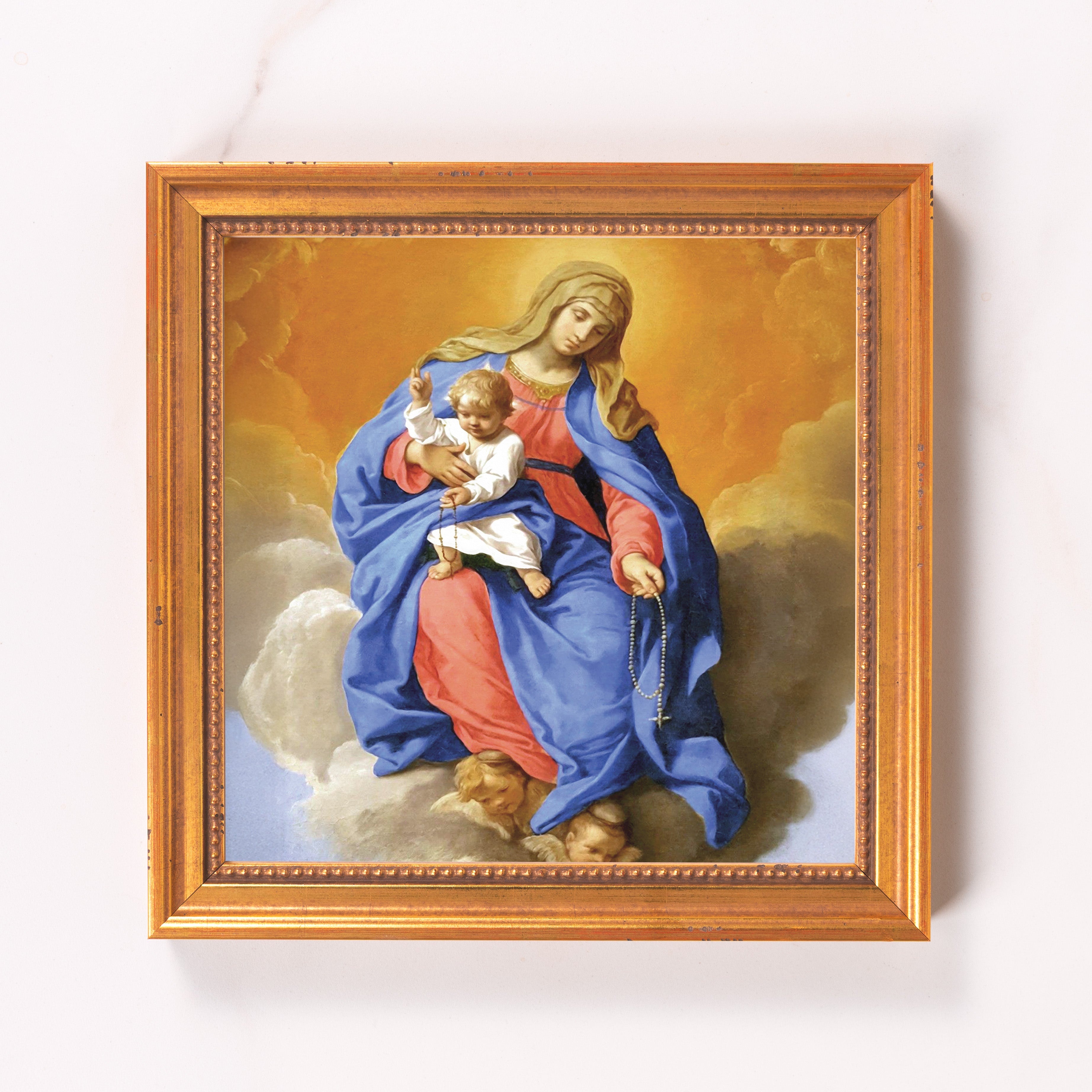 Framed artwork depicting Madonna and Child. Golden frame holds image with blue and pink robes over clouds and angels.