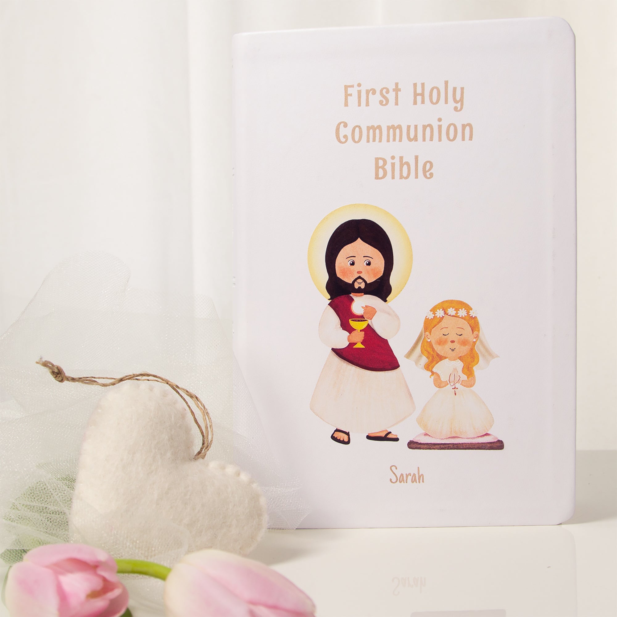 First Holy Communion Bible with Jesus and girl graphic on a white cover.