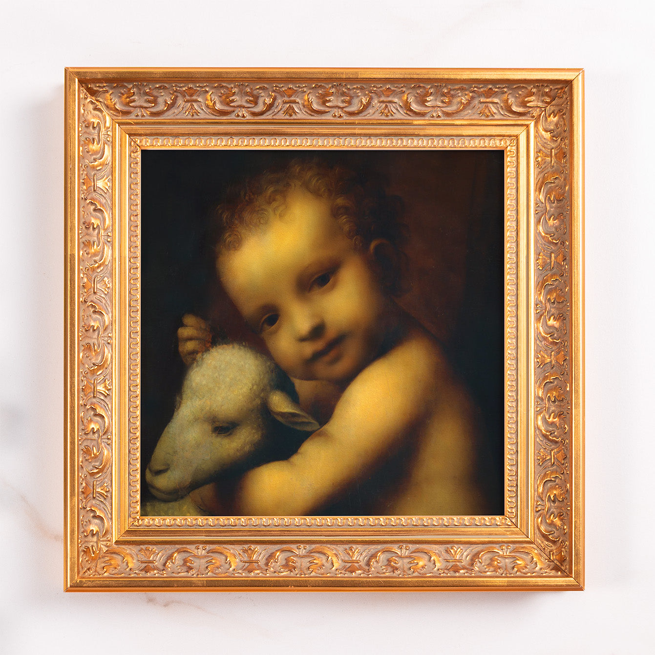 Framed oil painting of cherubic child embracing lamb in gold ornate frame.