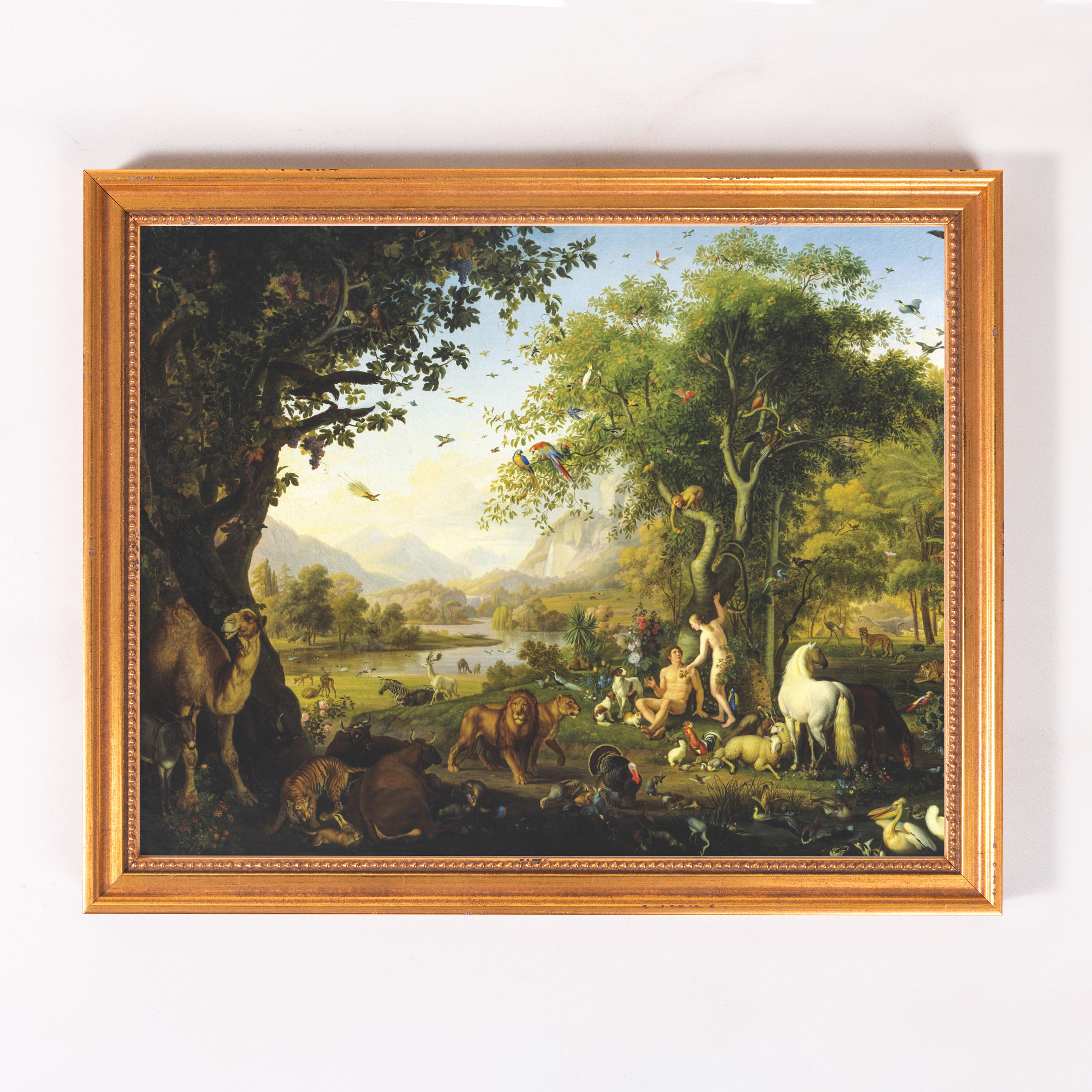 Framed oil painting depicting Adam and Eve in the Garden of Eden, featuring many animals and trees with a gold frame.