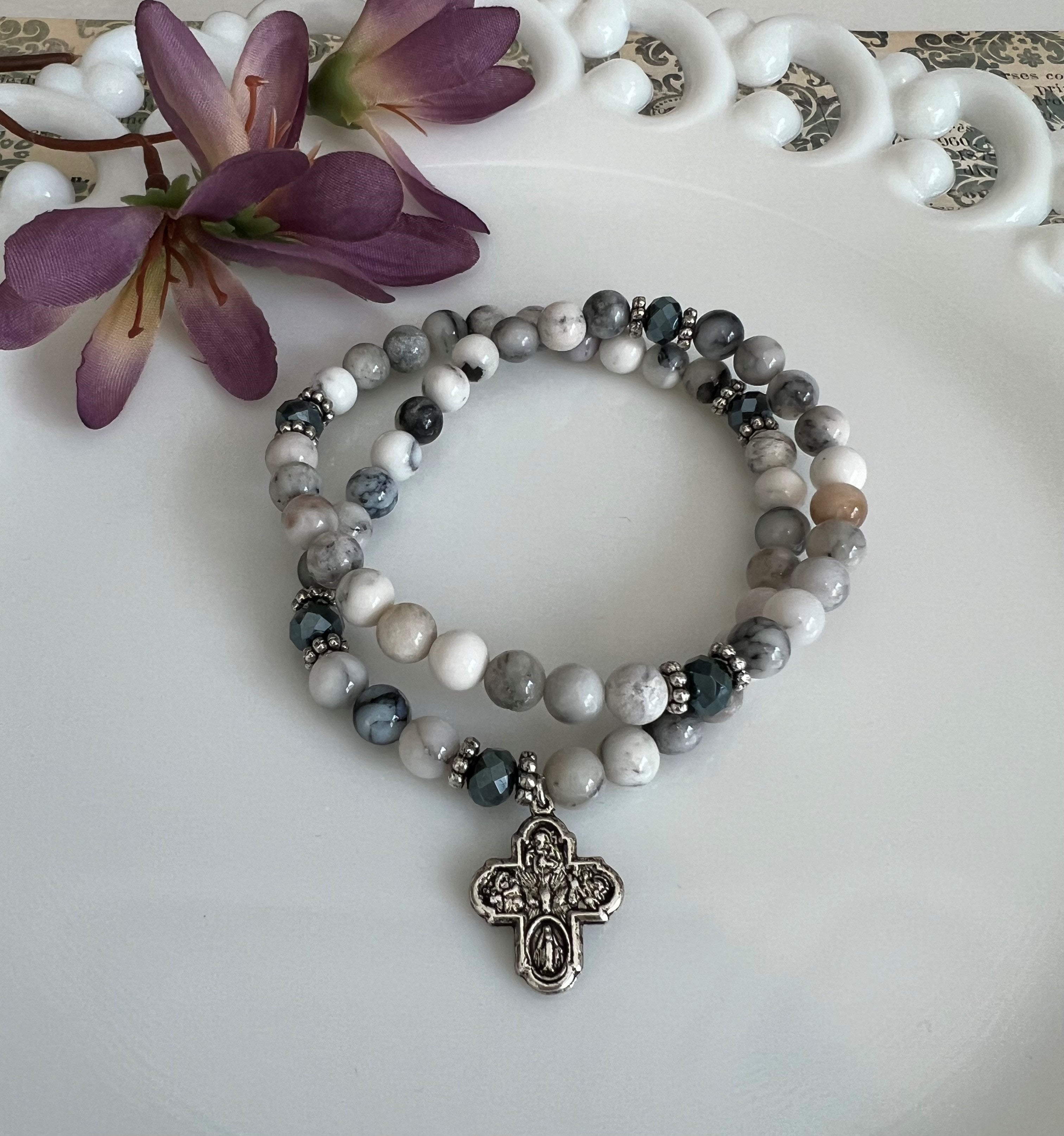 Handmade, beaded bracelet with a silver cross charm, crafted with gray and white stone beads and silver accents.