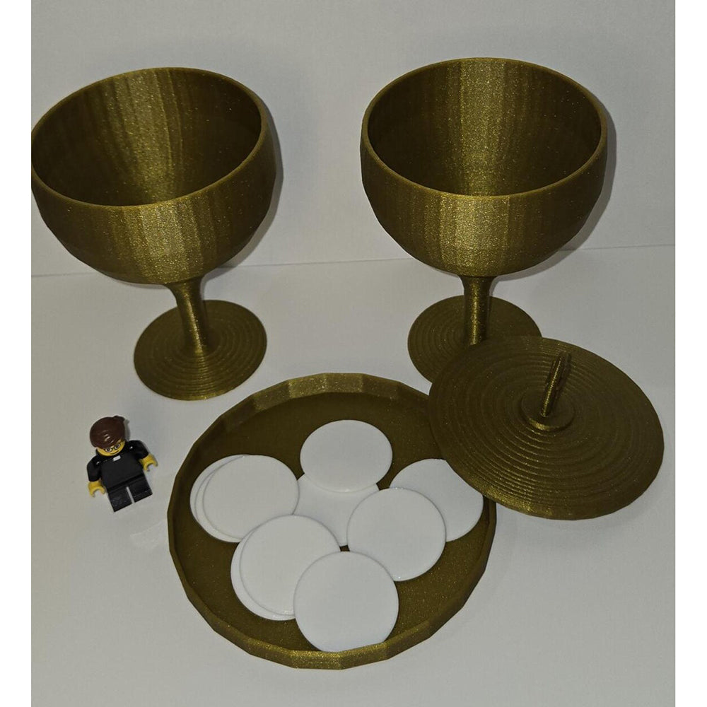 Communion set with two gold 3D-printed chalices, wafers on platter, and lid, next to a Lego figure.