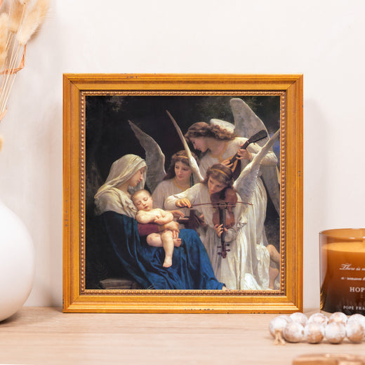 Framed print shows angels playing music to a baby in mother’s lap with a gold frame.