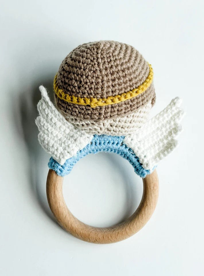 Crocheted baby rattle with wooden ring, brown and white wings, and a light blue accent.