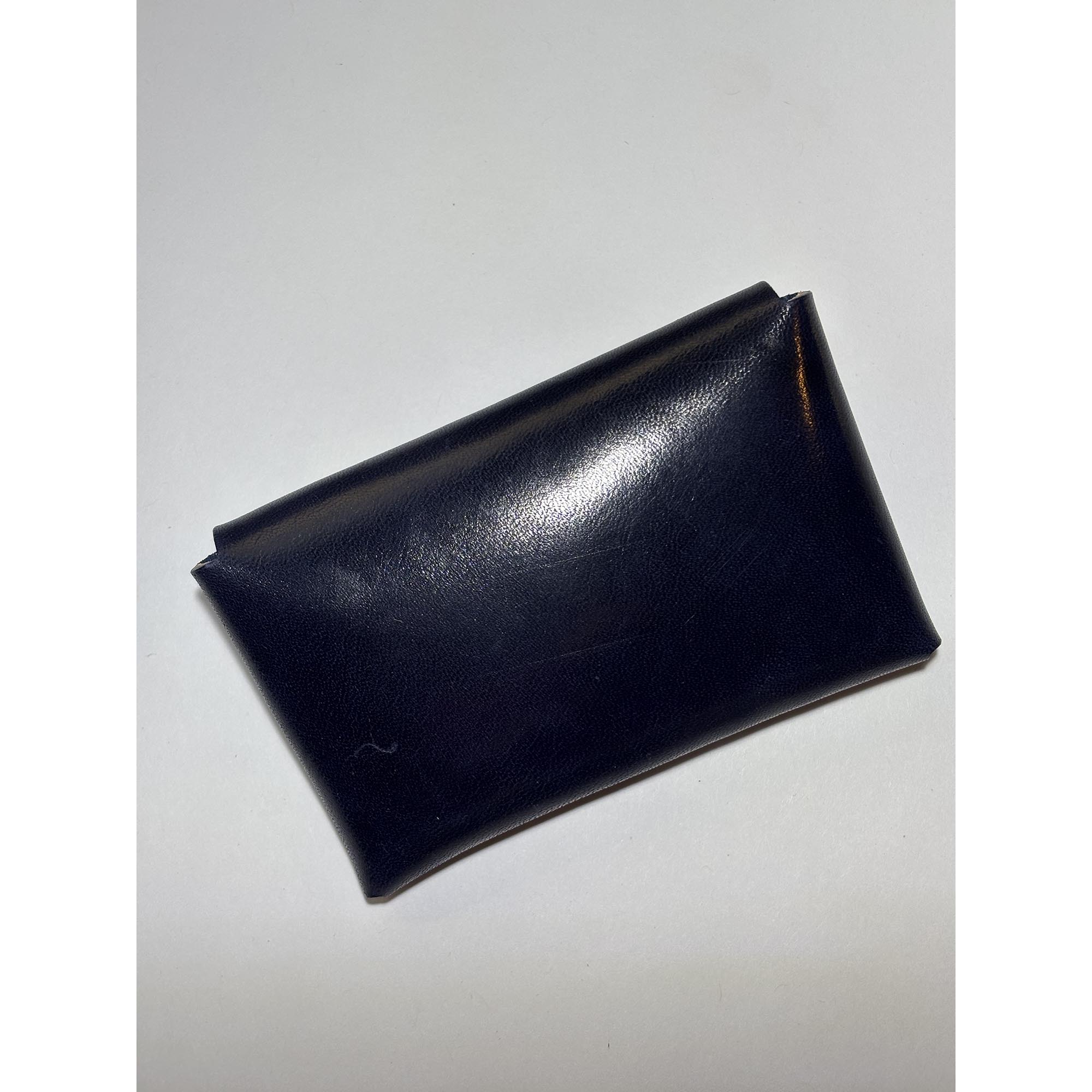 Black leather card wallet on a white surface.