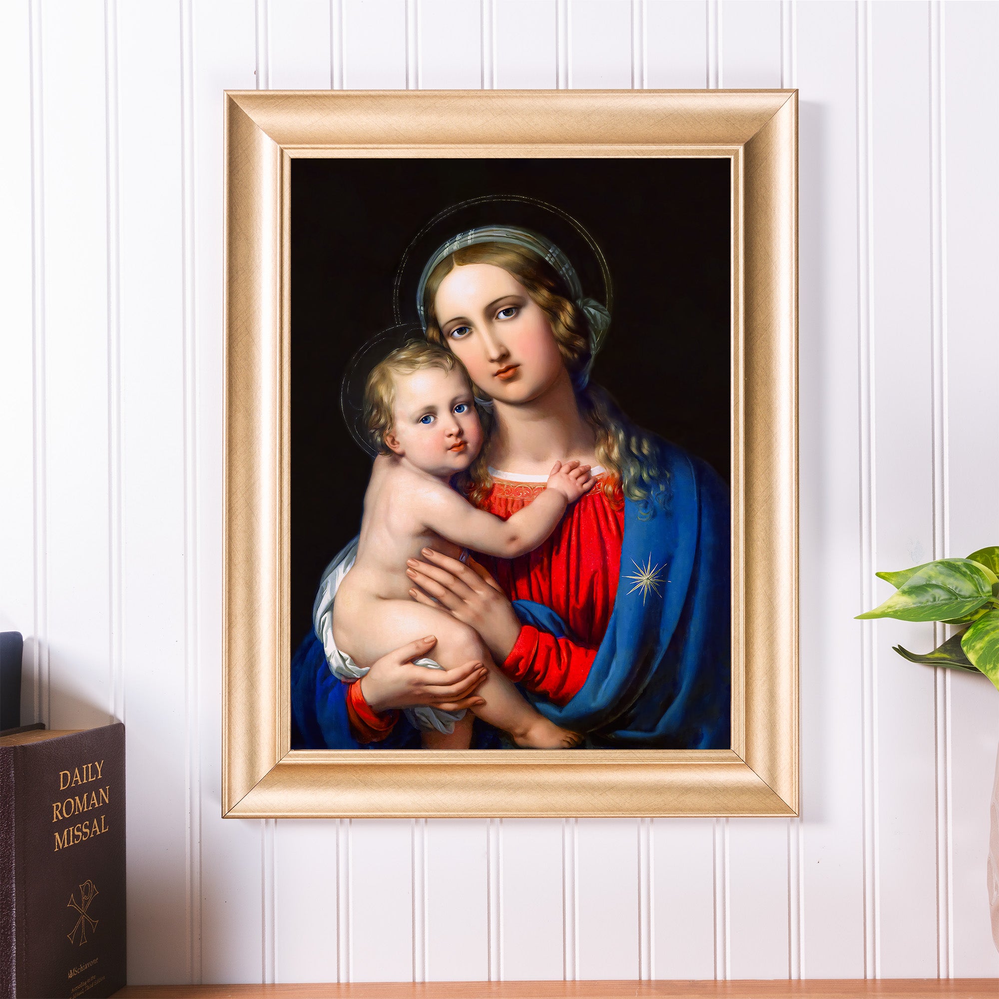 Framed painting of Mary holding baby Jesus, gold frame, red and blue clothing, dark background.