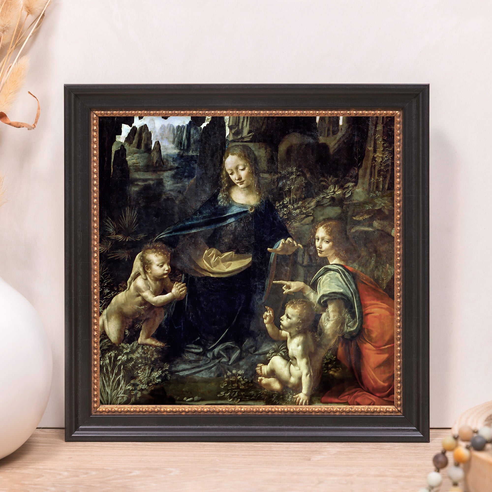 Framed print of Leonardo da Vinci's "Virgin of the Rocks" with a black and gold frame, Renaissance style.
