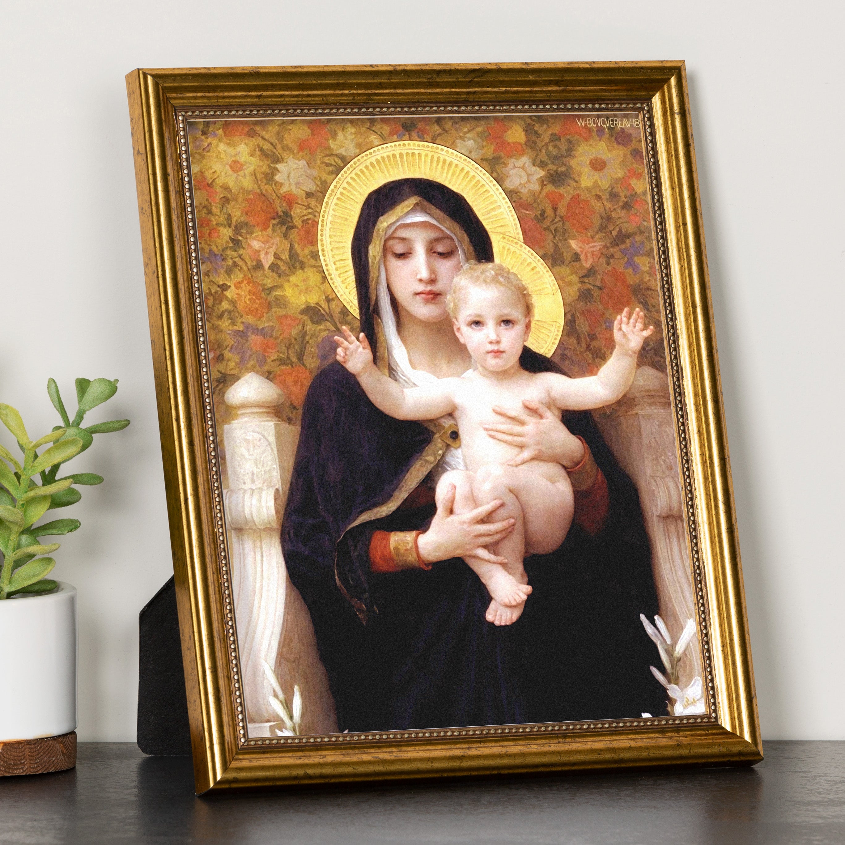 Framed print depicting Mary holding baby Jesus, featuring golden ornate frame and floral background.