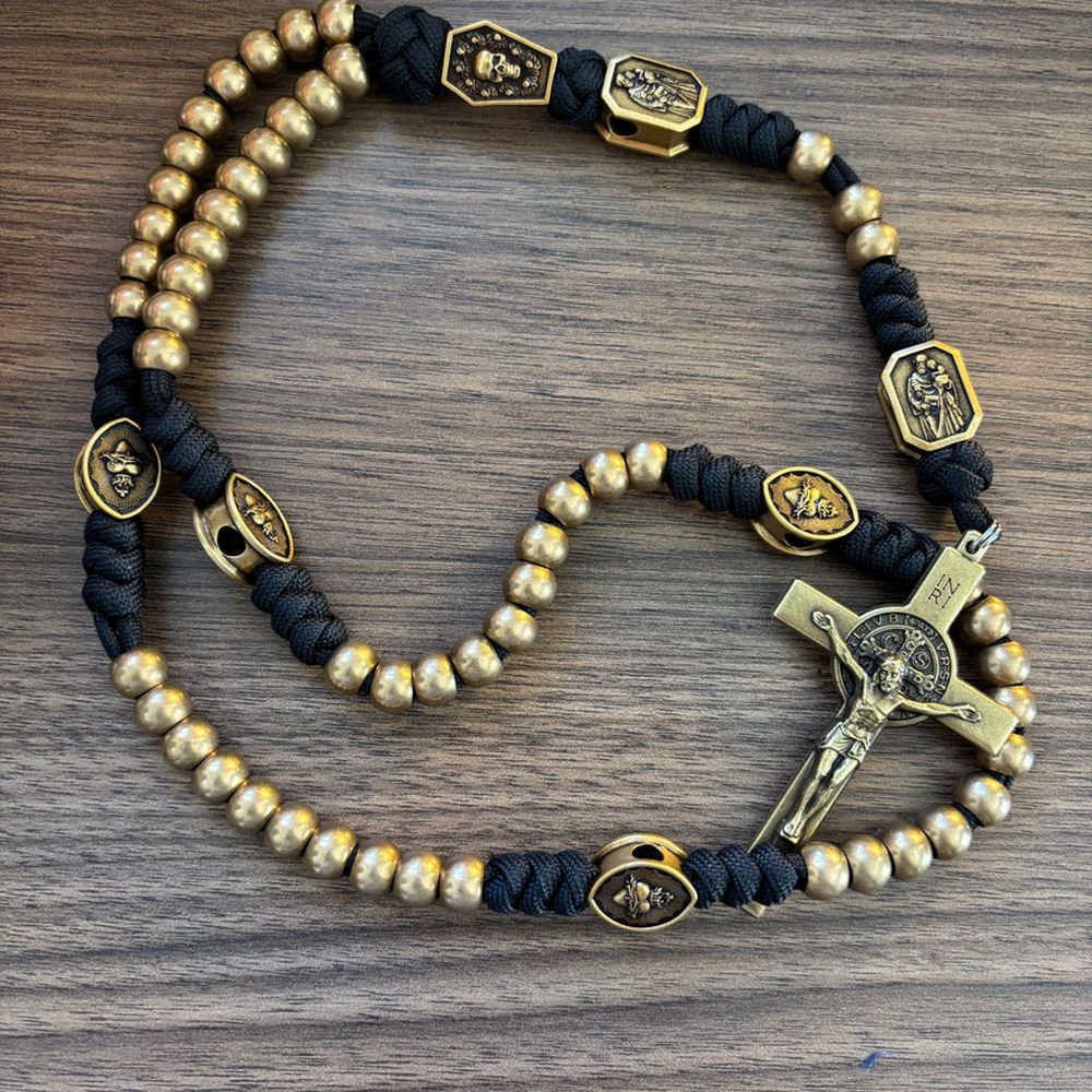 Religious rosary with gold beads, black knotted cord, and an ornate crucifix pendant.