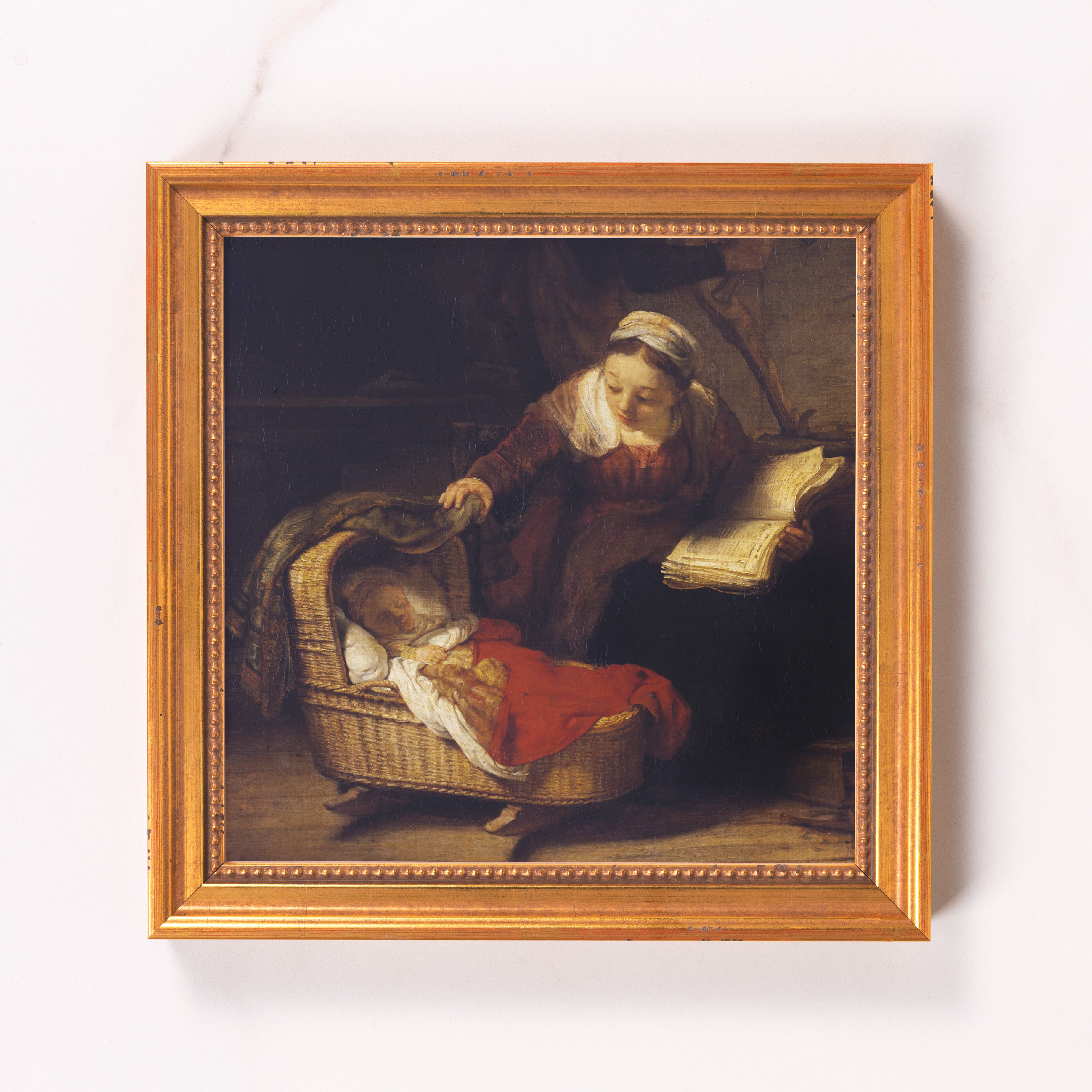 Framed oil painting of a woman with a book watching over a baby in a wicker crib.