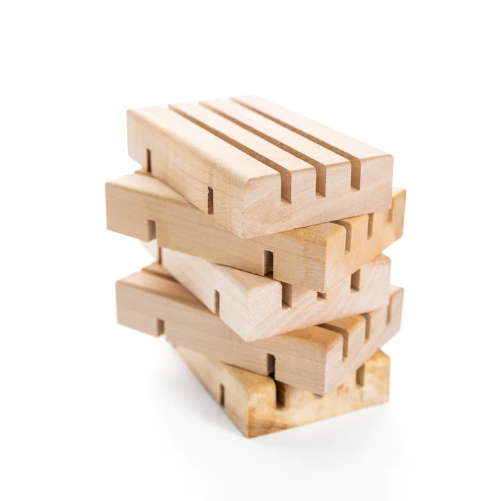 Stacked, Light-colored wooden soap dishes with grooved surface, for draining excess water.
