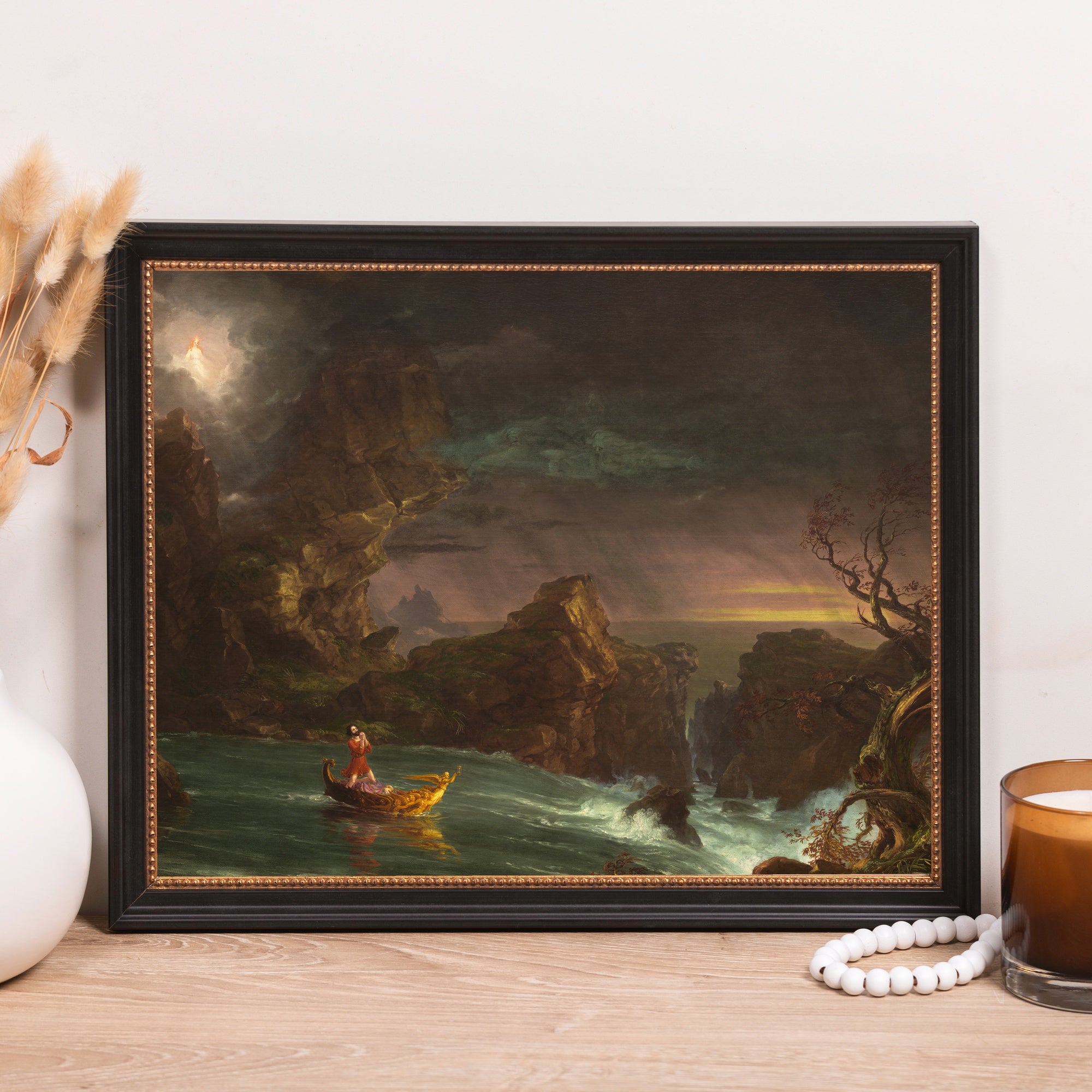 Framed vintage-style art print of a man in a boat near dark cliffs and rough water.