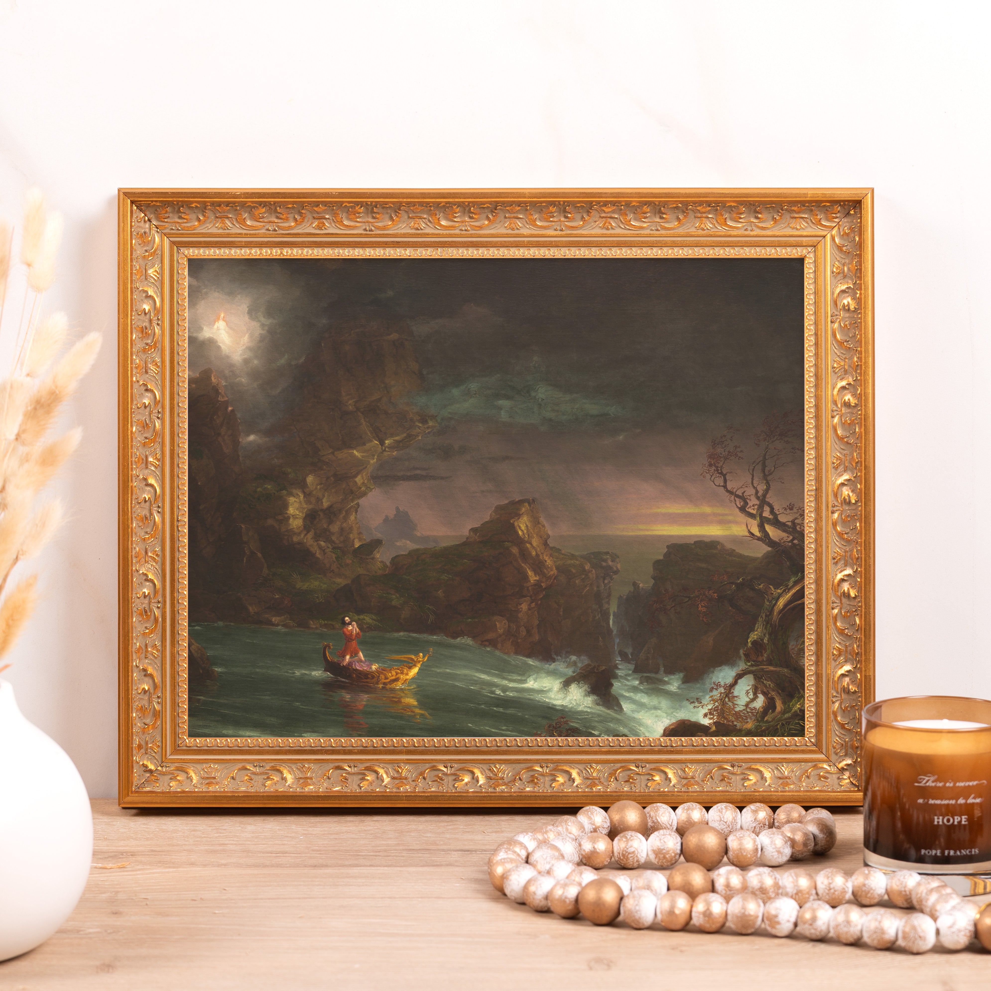 Framed painting of a man on a boat in a stormy sea in gold ornate frame.