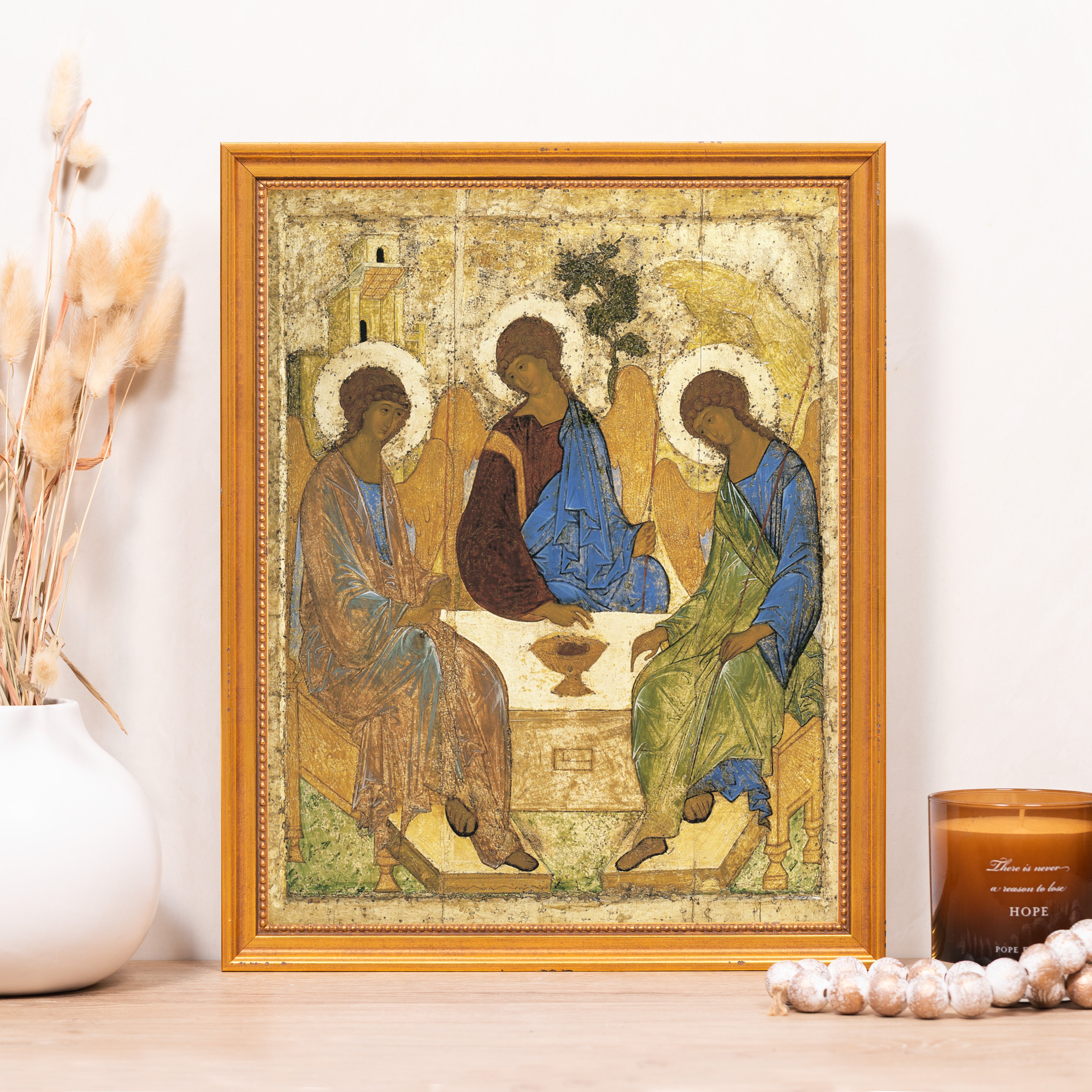Religious painting depicts three figures with halos, in a gold frame and textured style.