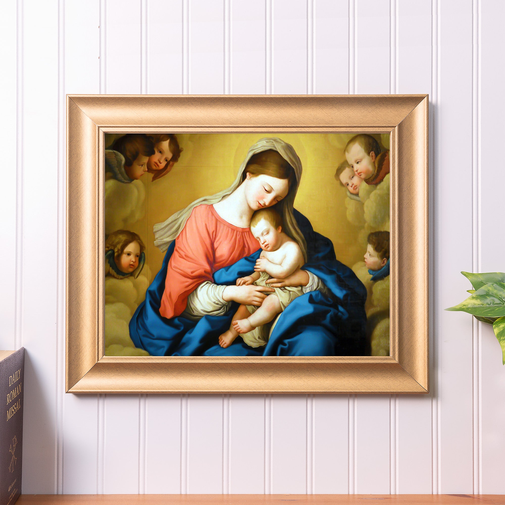 Framed artwork of Virgin Mary and baby Jesus with angel cherubs in a gold frame.