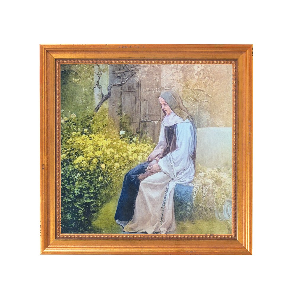 Framed print of a nun seated in a garden, in a gold-toned frame.